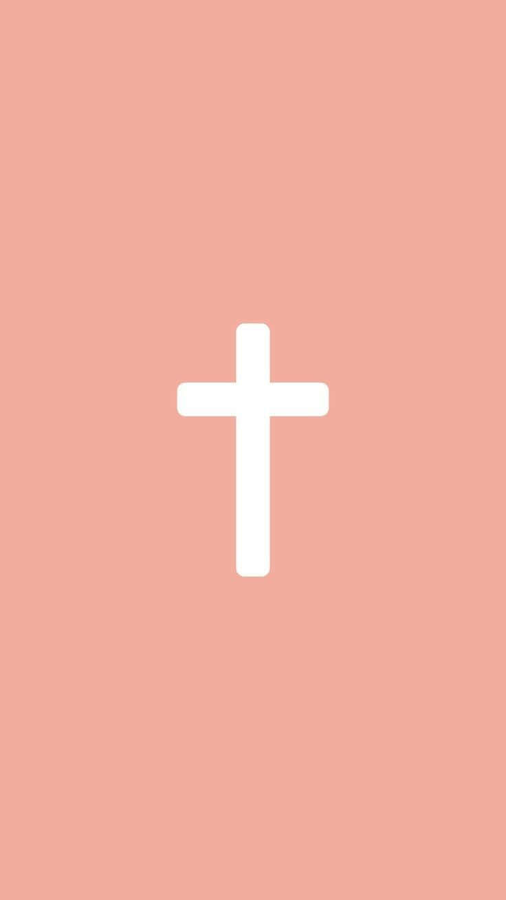 Pink Cross 桌布 壁紙 — 一個簡約的白色十字架置於柔和蜜桃色背景中央，營造出寧靜而靈性的視覺效果。