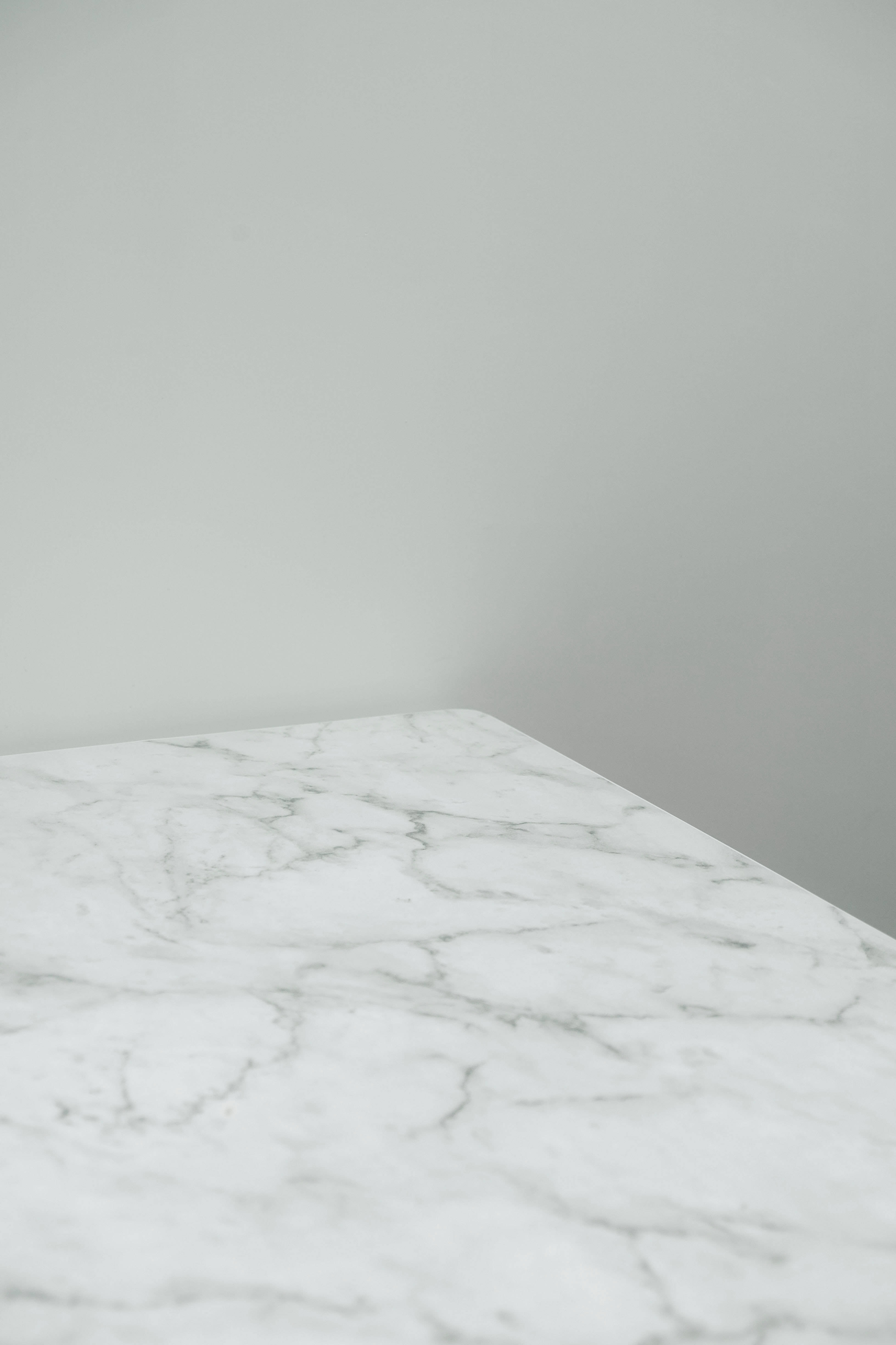 White Marble 桌布 壁紙 — 一個簡約的白色大理石桌面，帶有灰色紋理，在乾淨的現代室內設計中與純灰色牆壁相遇。