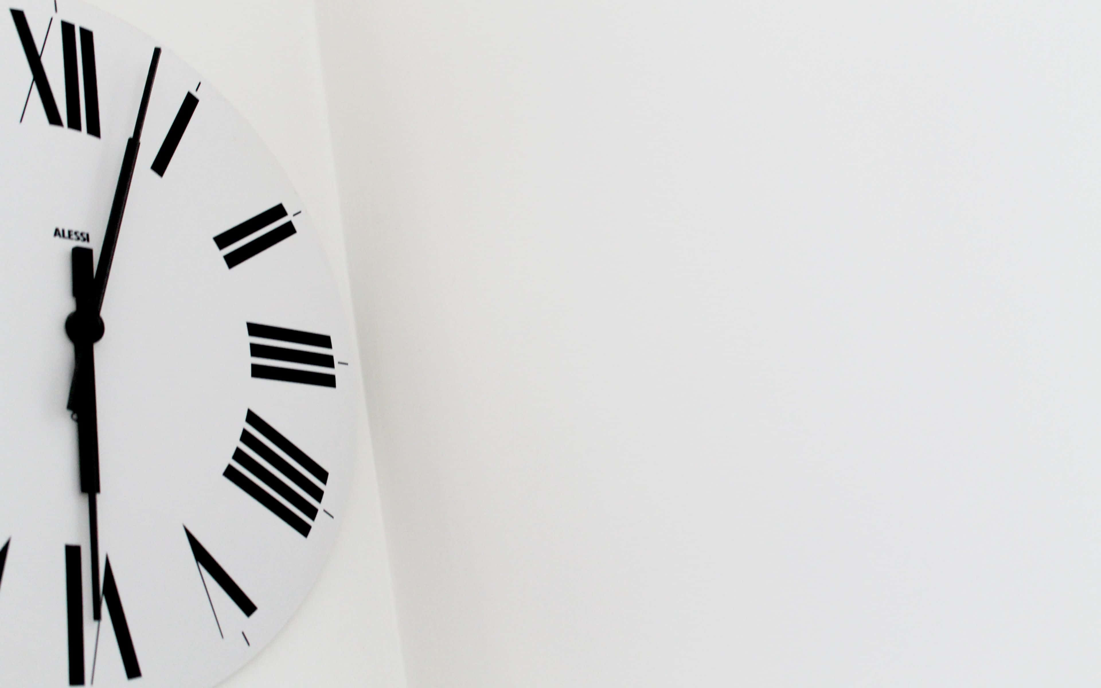 Clock 桌布 壁紙 — 一個簡約的白色掛鐘，帶有黑色羅馬數字和指針，在純白色背景上顯示時間。