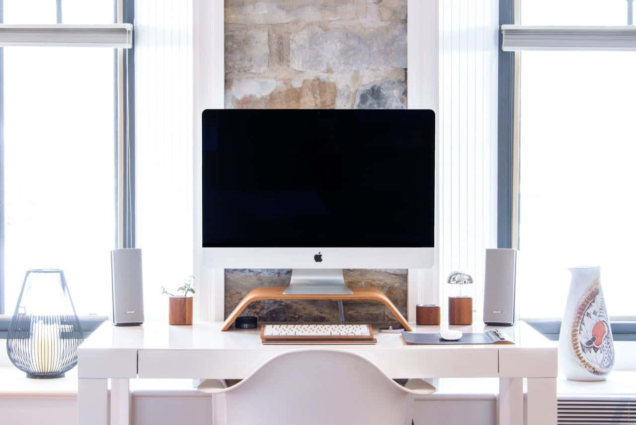 背景 桌布 壁紙 — 一個簡約的白色桌面設置，配備 iMac、揚聲器和裝飾物品，在明亮的窗光下。