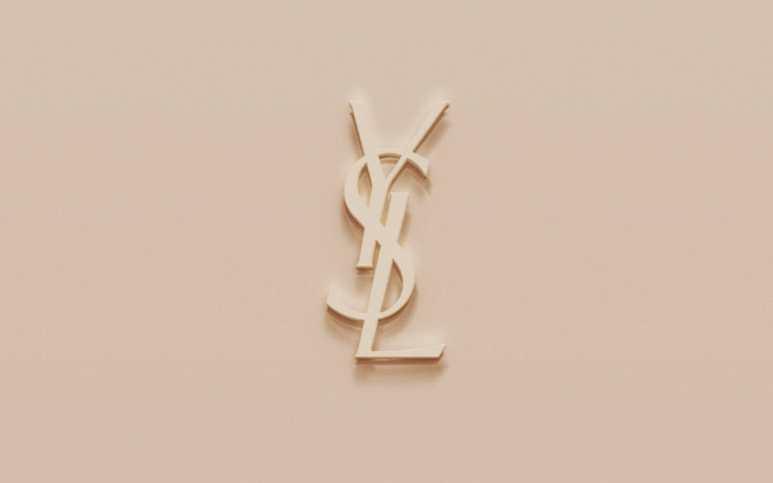 Ysl 桌布 壁紙 — 一個簡約的米色YSL字母組合標誌居中放置在柔軟的紋理牆上，帶有微妙的陰影。