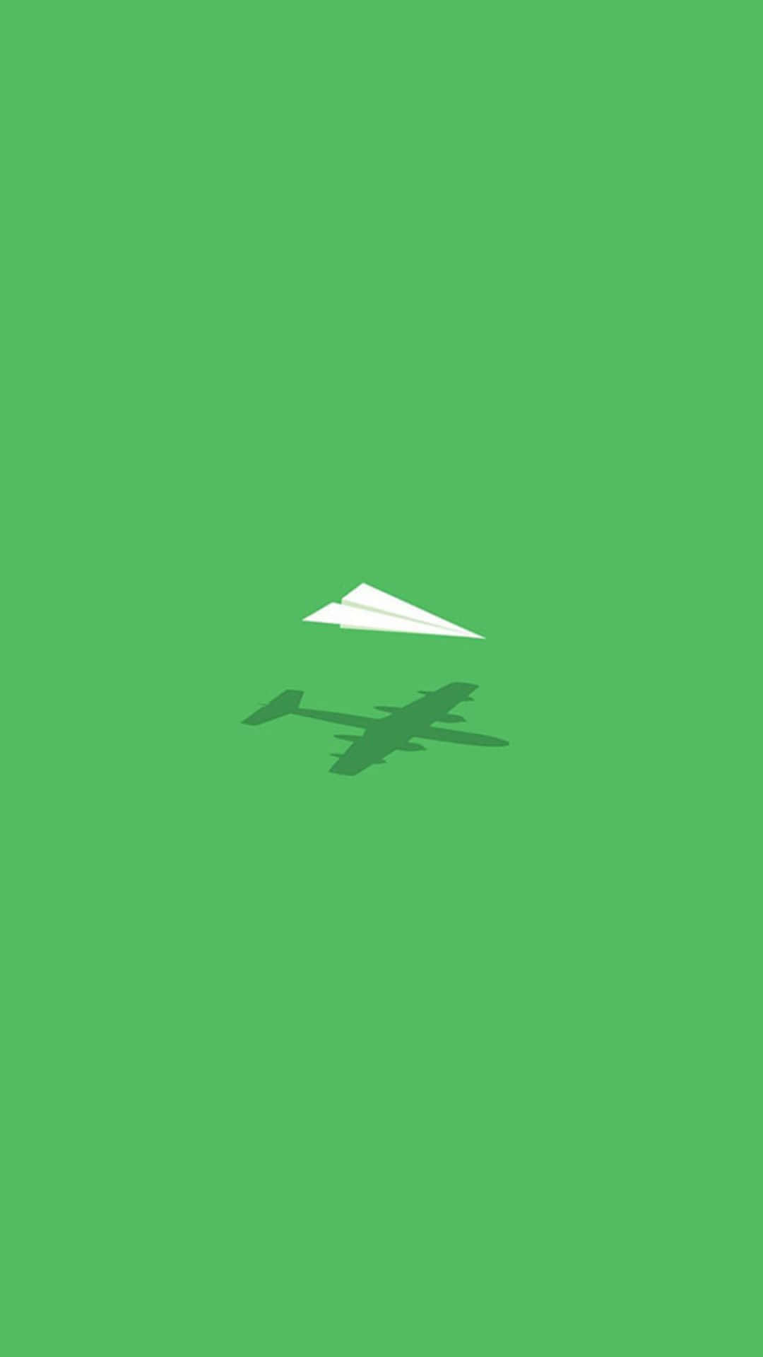 Android Small Planes 桌布 壁紙 — 一個簡約的綠色背景，上面有一架白色紙飛機在較深色的綠色飛機剪影上方翱翔。