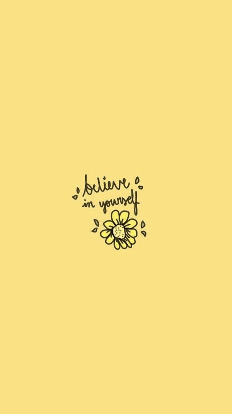 Positive Quotes 桌布 壁紙 — 一個簡約的黃色背景，上面有黑色草書寫著「相信自己」，下方有一個簡單的花朵塗鴉。