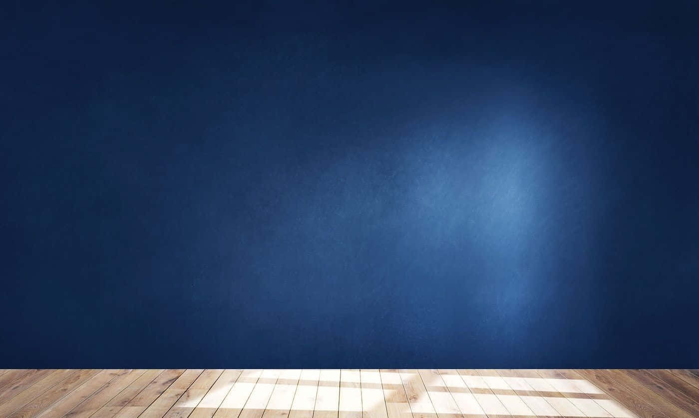 Empty Room 桌布 壁紙 — 一個簡約風格的房間，鋪有木地板和深藍色紋理牆壁，柔和陽光照射出幾何陰影。