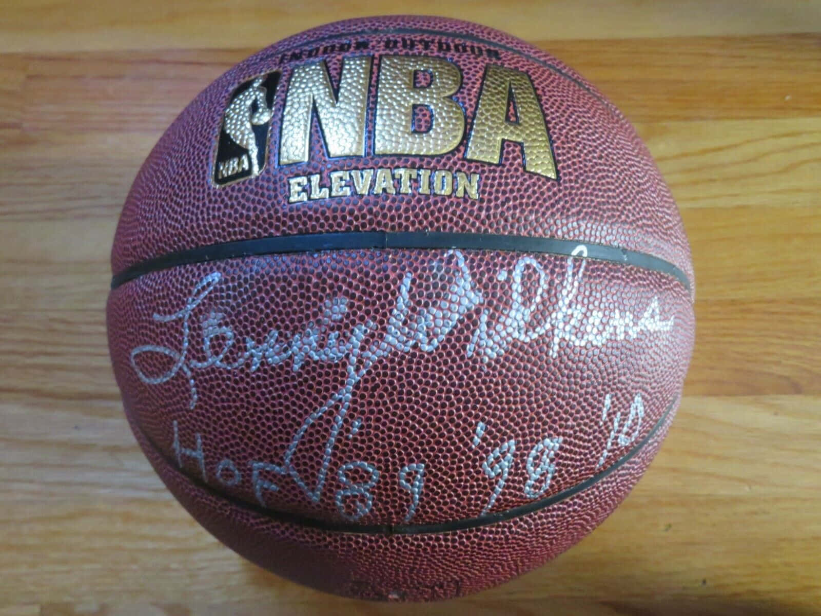 NBA 桌布 壁紙 — 一個簽名的NBA Elevation籃球，上面有Lenny Wilkens的簽名和名人堂年份，放在木地板上。