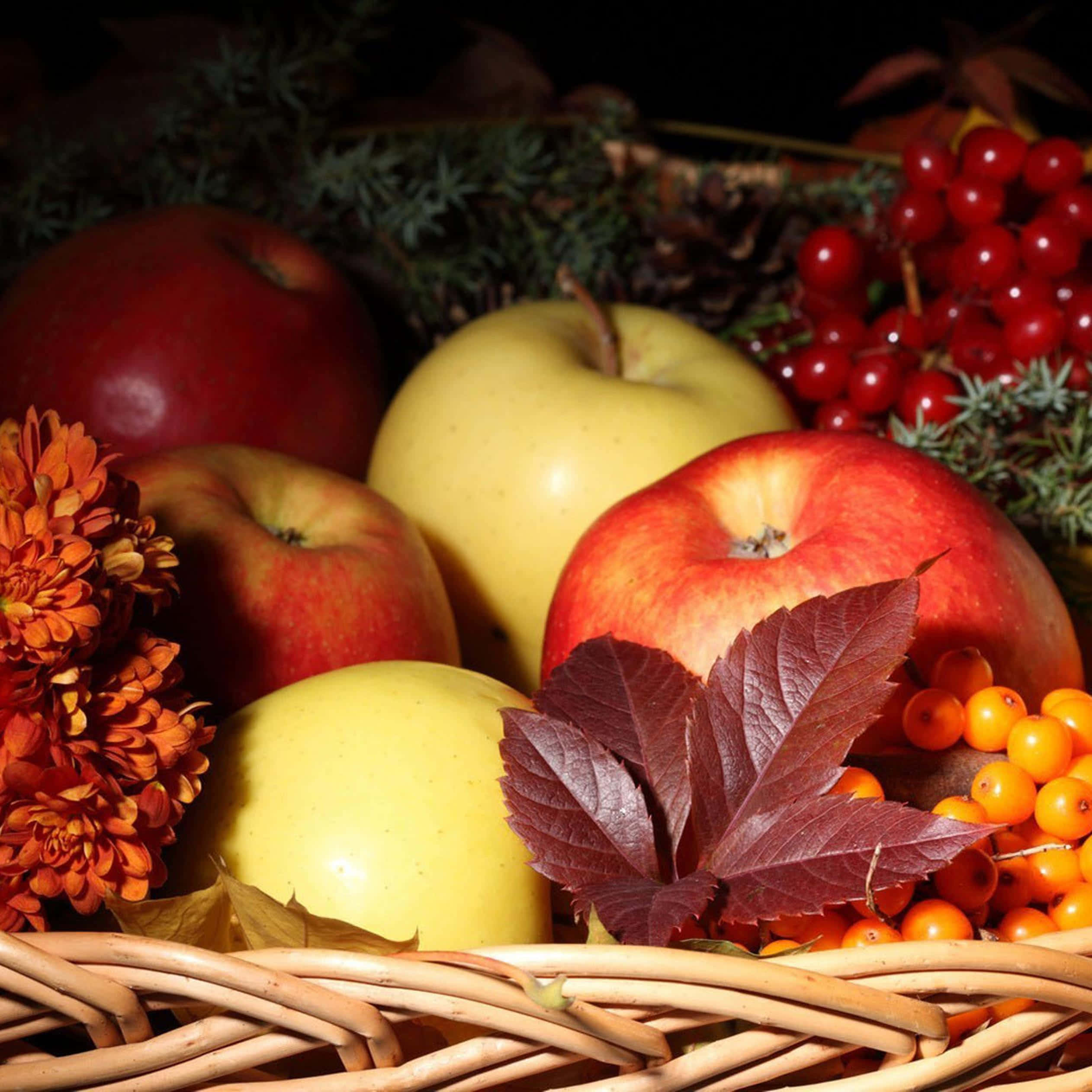 Autumn Food 桌布 壁紙 — 一個籃子裝滿了紅蘋果、黃蘋果、鮮豔的漿果和秋葉，在溫暖的方向性燈光下。