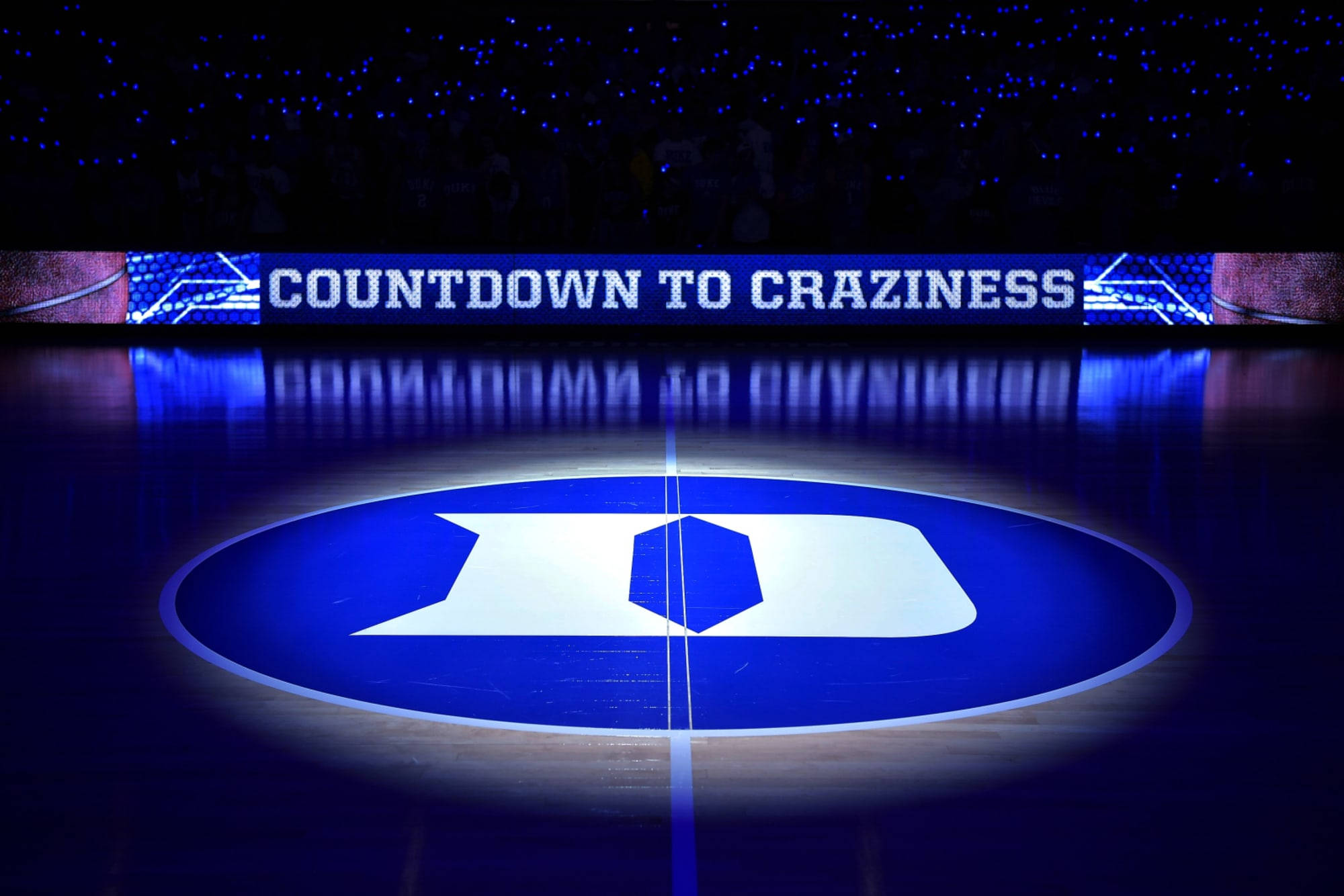 Duke Blue Devils 桌布 壁紙 — 一個籃球場，中央球場標誌以藍色燈光照明，上方有 'COUNTDOWN TO CRAZINESS' 計分板。