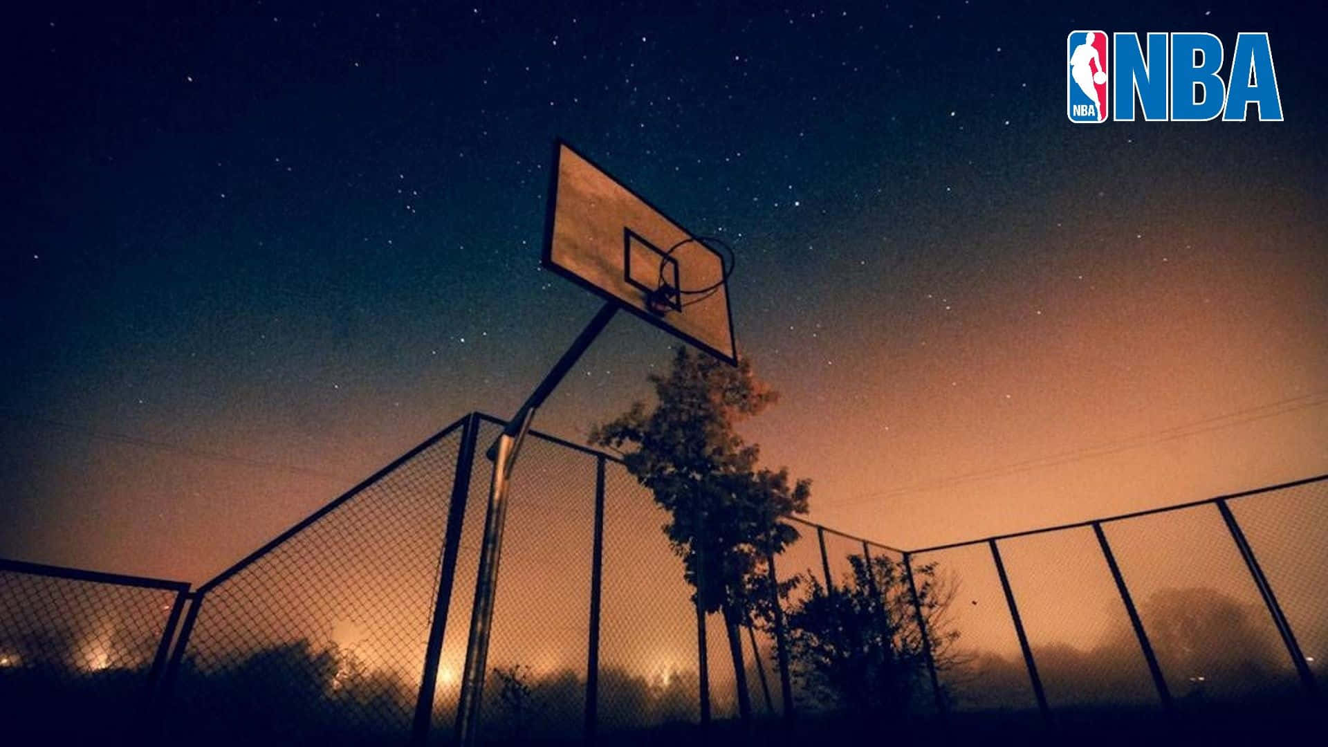 Basketball Court 桌布 壁紙 — 一個籃球框在繁星點點的夜空下呈現剪影，地平線上有橙色光芒。