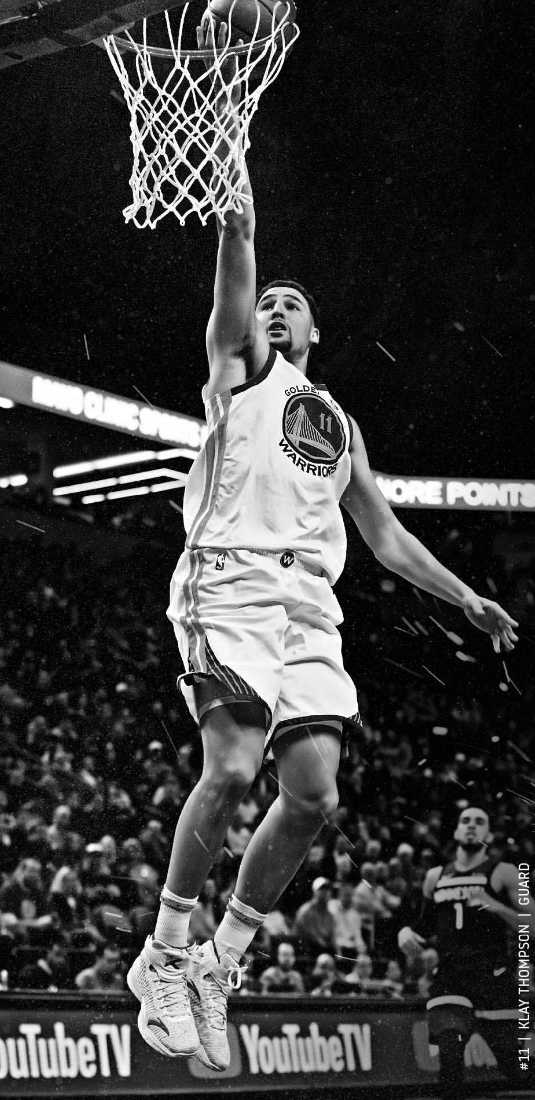 Thompson 桌布 壁紙 — 一個籃球運動員在半空中專注地灌籃，場館內紙屑如雨般落下，全場爆滿。