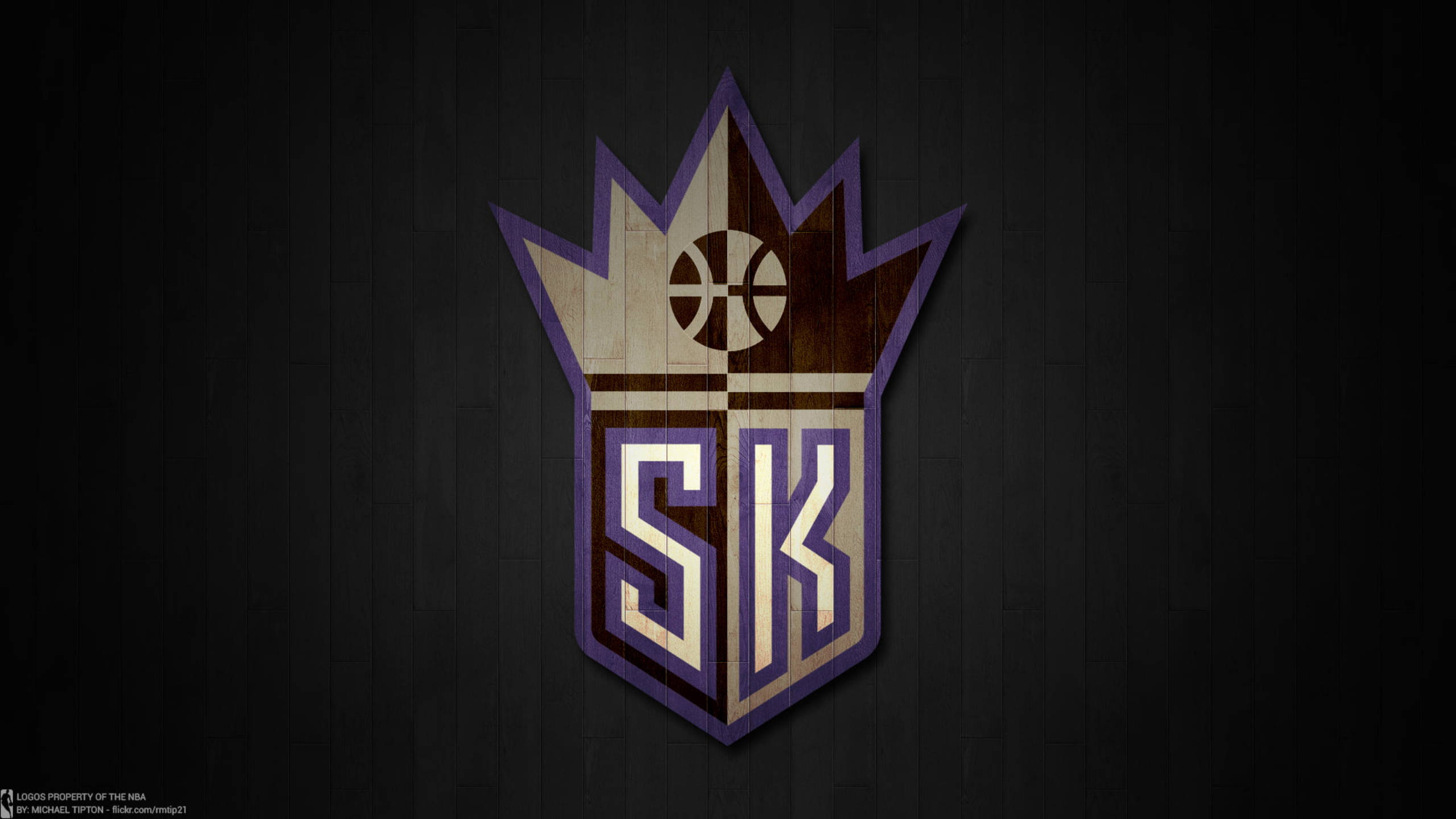 Sacramento Kings 桌布 壁紙 — 一個籃球隊標誌，帶有皇冠和「SK」字母，背景為深色木牆。