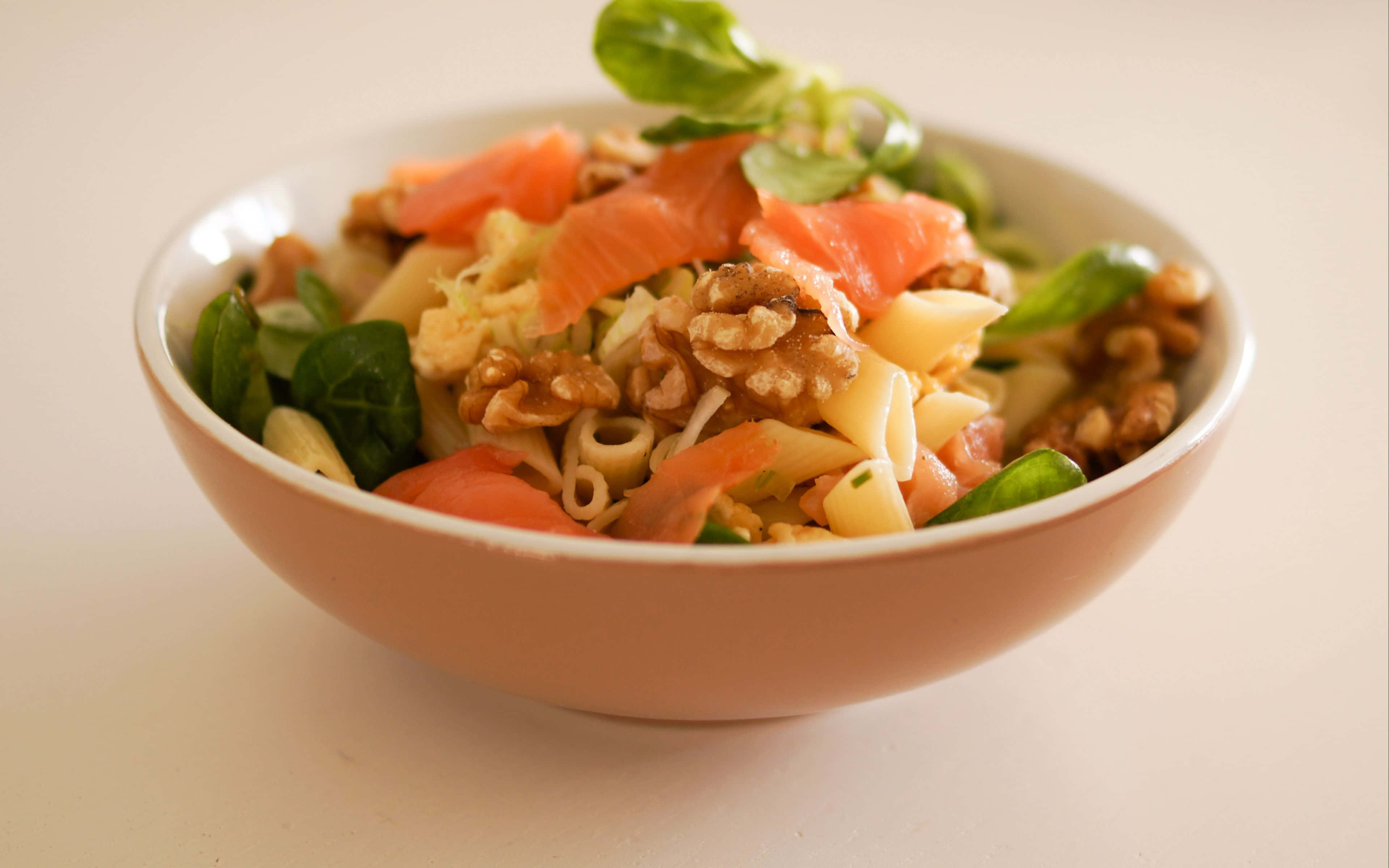 4K Pasta 桌布 壁紙 — 一個米色碗中的奶油義大利麵沙拉特寫，上面放有煙燻鮭魚、核桃和新鮮蔬菜。