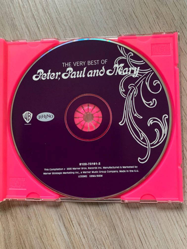 音樂 桌布 壁紙 — 一個粉紅色CD盒內含一張紫色的Peter Paul and Mary合輯光碟，放在木質表面上。