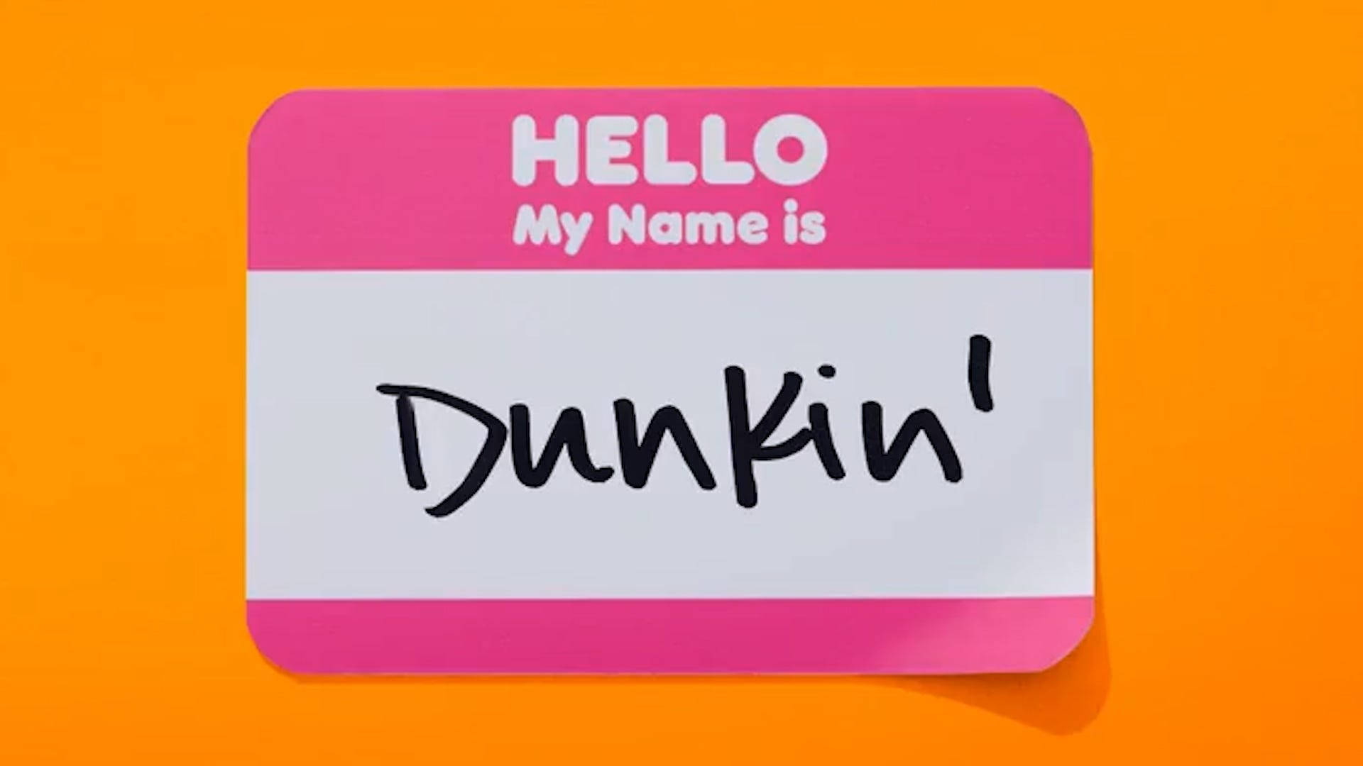donuts 桌布 壁紙 — 一個粉紅色和白色的名牌，上面寫著「Hello My Name Is Dunkin」，背景是鮮豔的橙色。