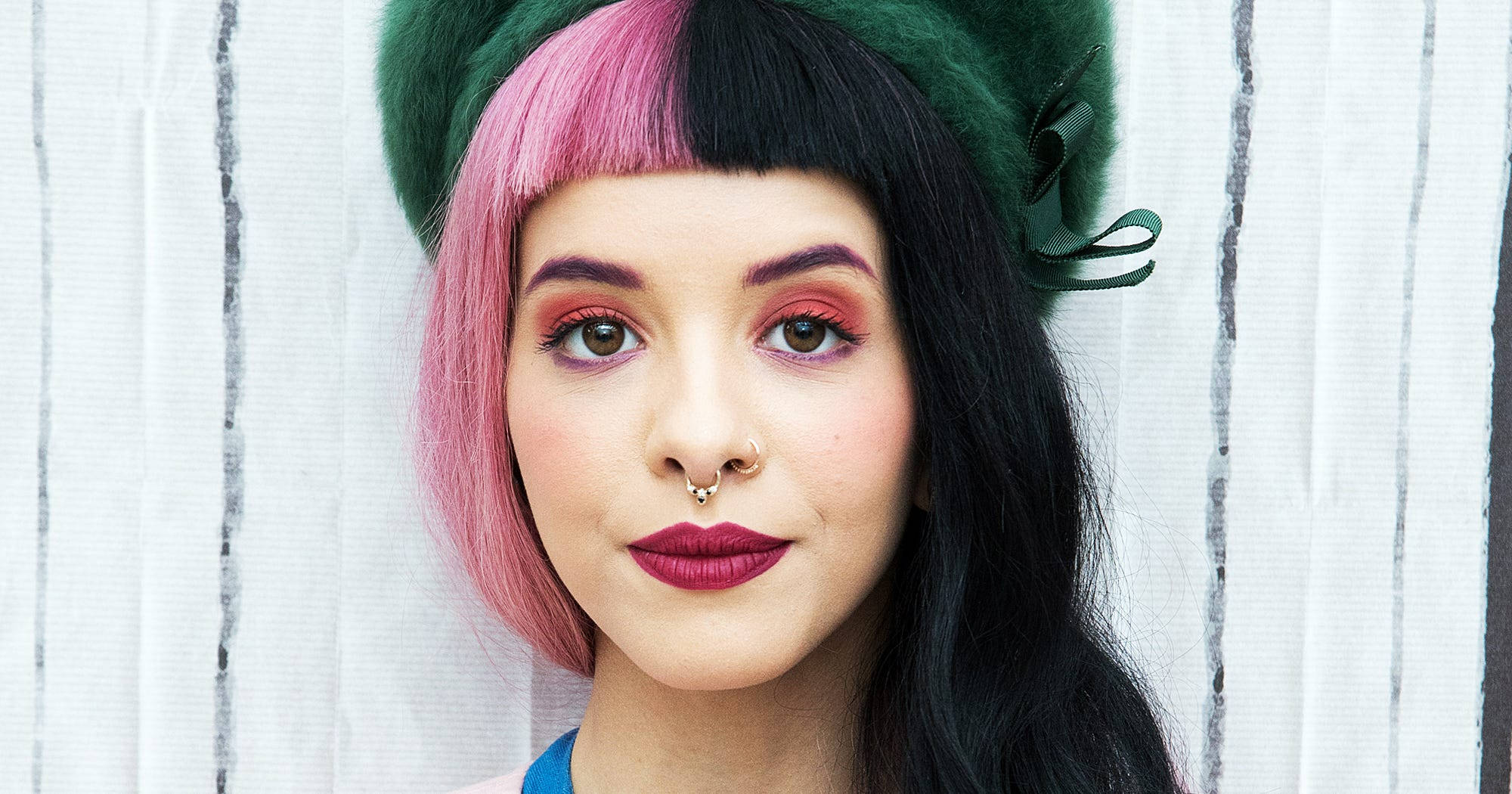 Melanie 桌布 壁紙 — 一個粉紅色和黑色頭髮的人戴著綠色貝雷帽，背景是白色木柵欄。