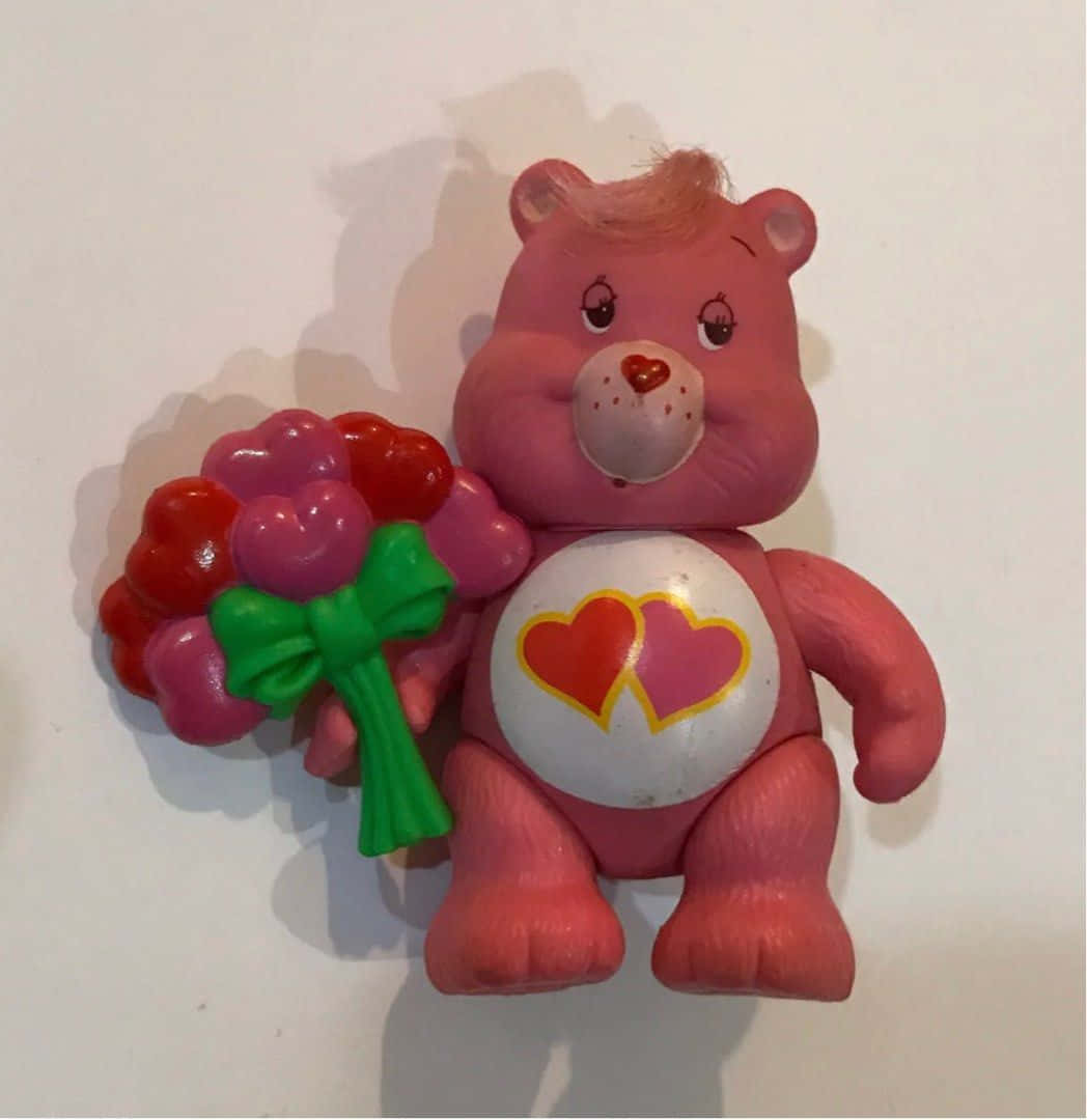 彩虹熊 桌布 壁紙 — 一個粉紅色塑膠Care Bear玩具，在純白色背景上拿著一個心形花束。