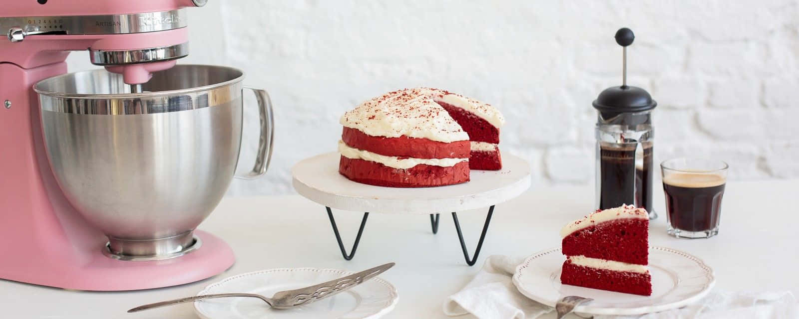 Red Velvet Cake 桌布 壁紙 — 一個粉紅色座枱攪拌機放在一個白色大理石架上，旁邊有一個紅絲絨蛋糕配奶油乳酪糖霜。