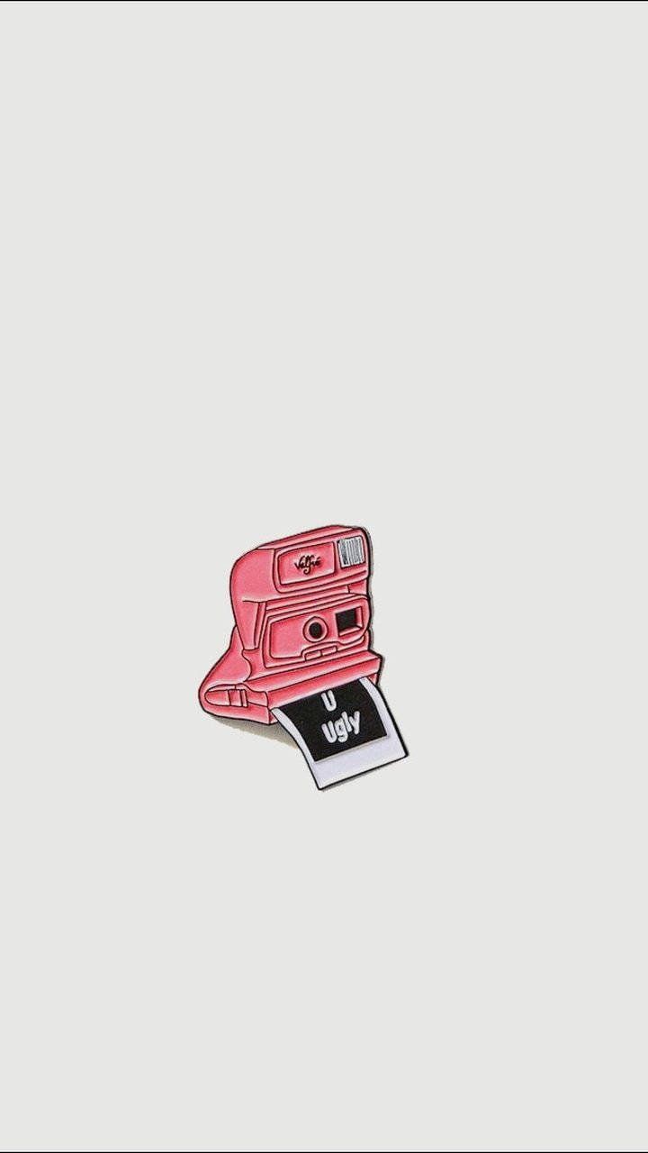 retro aesthetic iPhone 桌布 壁紙 — 一個粉紅色復古拍立得相機別針，附有一張照片彈出，上面寫著 u ugly，背景為淺灰色。