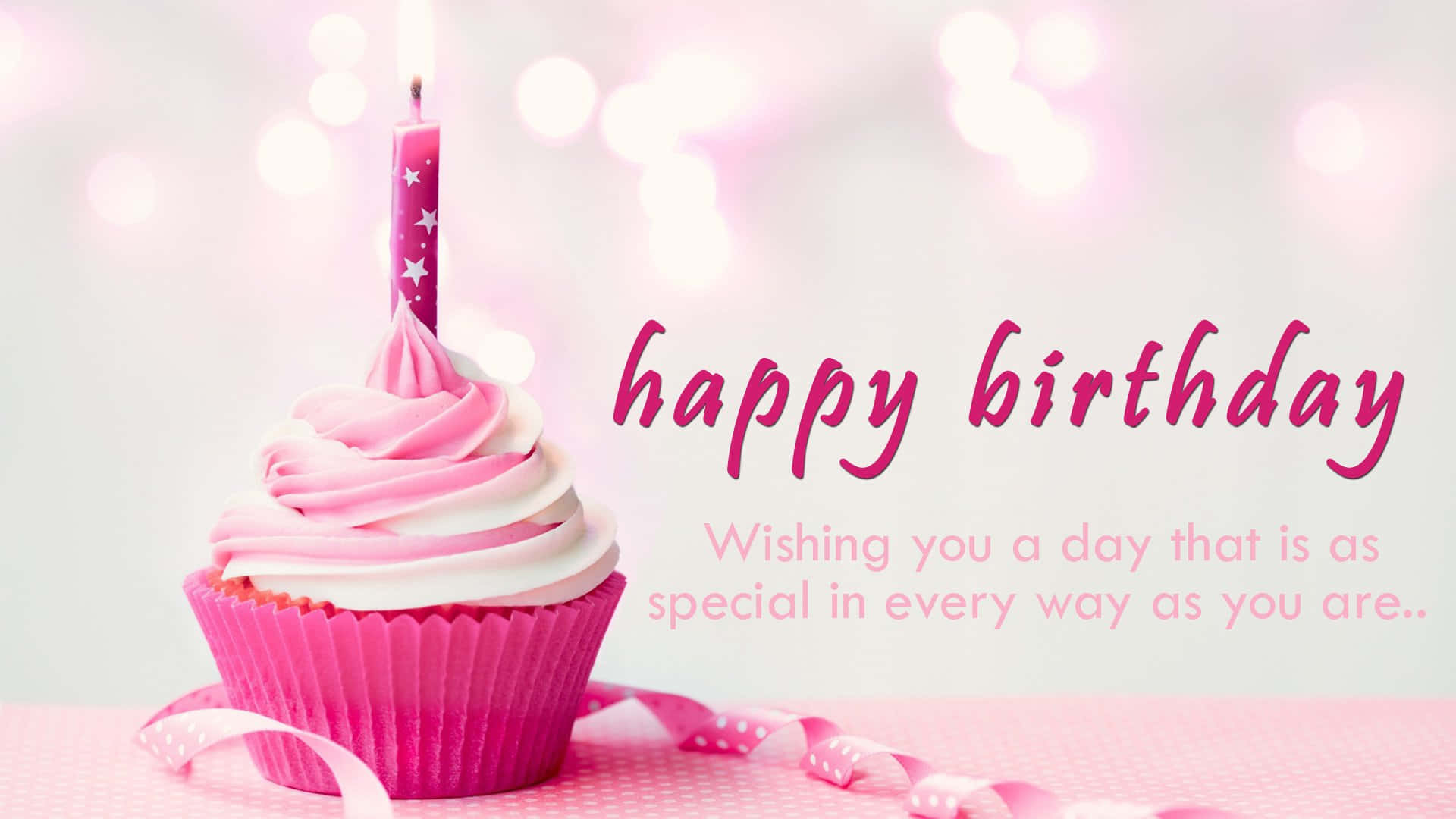 Birthday Wishes 桌布 壁紙 — 一個粉紅色杯子蛋糕，上面有燃燒的蠟燭和節日絲帶，旁邊是歡樂的生日祝福語，背景是柔和散景。