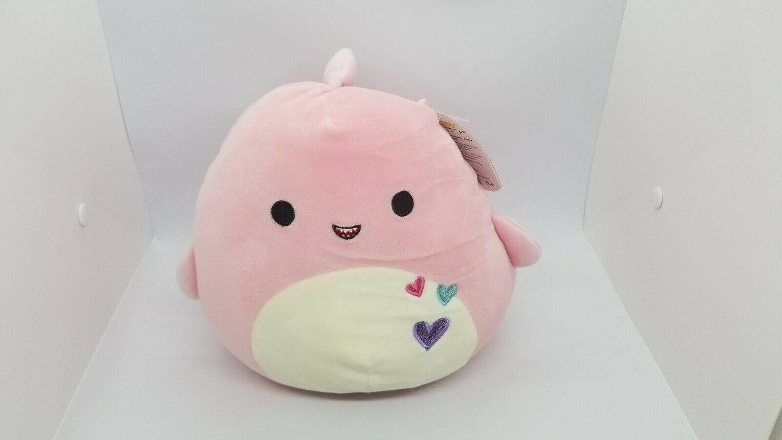 白色盒子裡肚子上有心形圖案的粉紅色毛絨玩具 — Squishmallows 壁紙