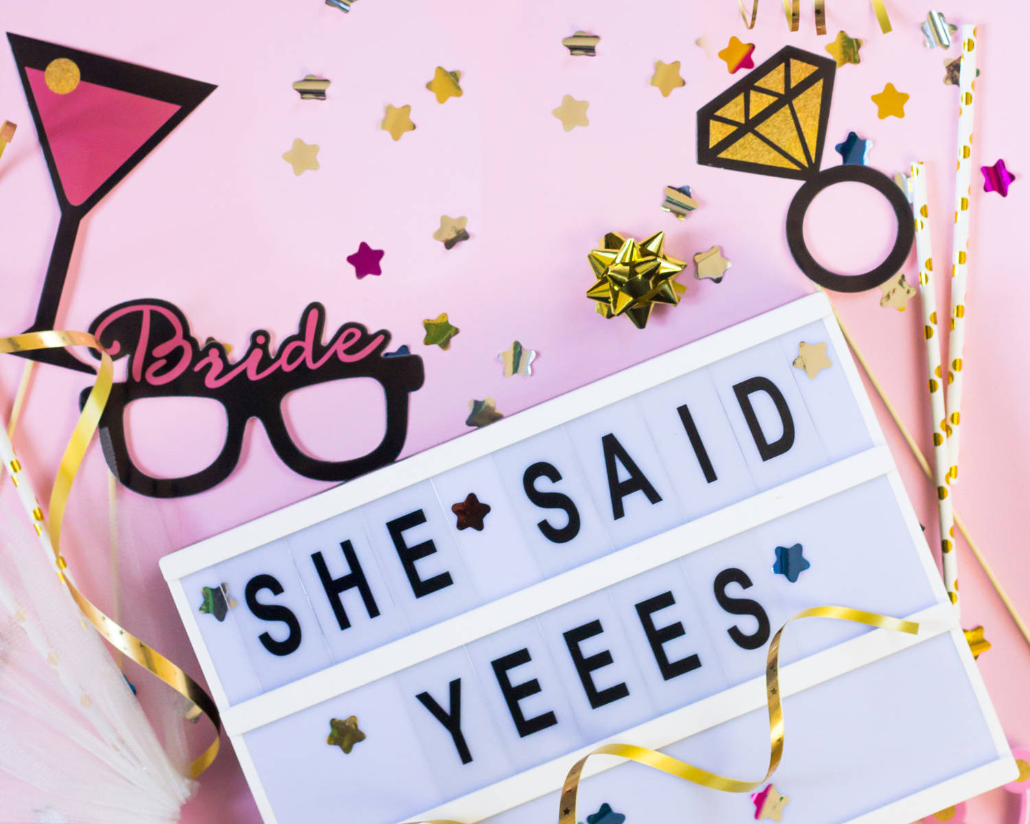 Bachelorette 桌布 壁紙 — 一個粉紅色的平鋪佈置慶祝準新娘，以一個寫著 'SHE SAID YEEES' 的燈箱為中心，周圍環繞著五彩紙屑、酒杯和鑽石戒指道具。