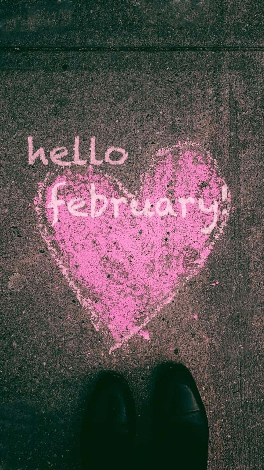 February iPhone 桌布 壁紙 — 一個粉紅色粉筆心形，裡面寫著hello february，在深色路面上，從上方俯瞰，底部有黑色鞋子。