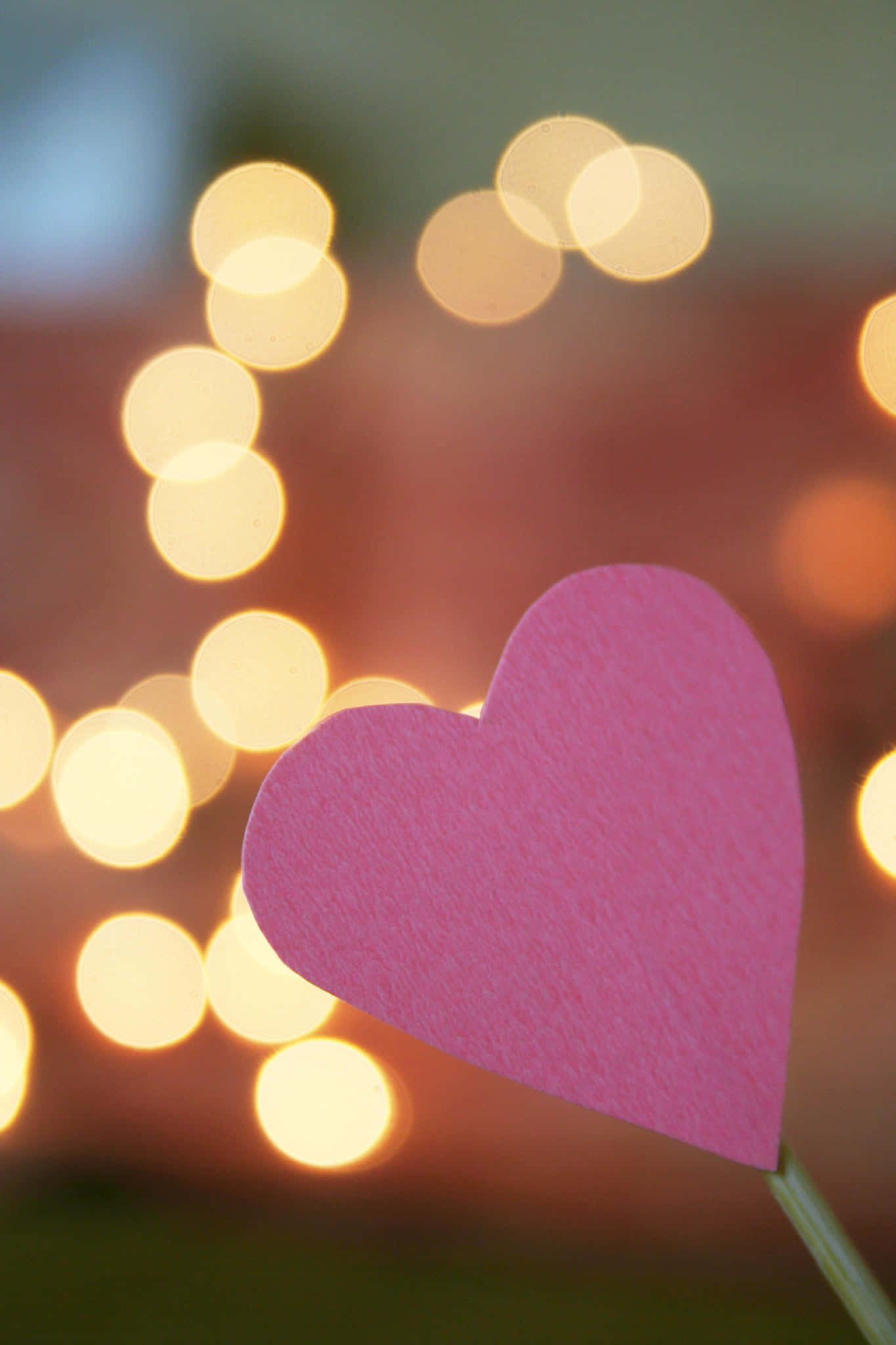 Heart Shape 桌布 壁紙 — 一個粉紅色紙愛心在溫暖散景背景中，閃爍的燈串下清晰對焦。