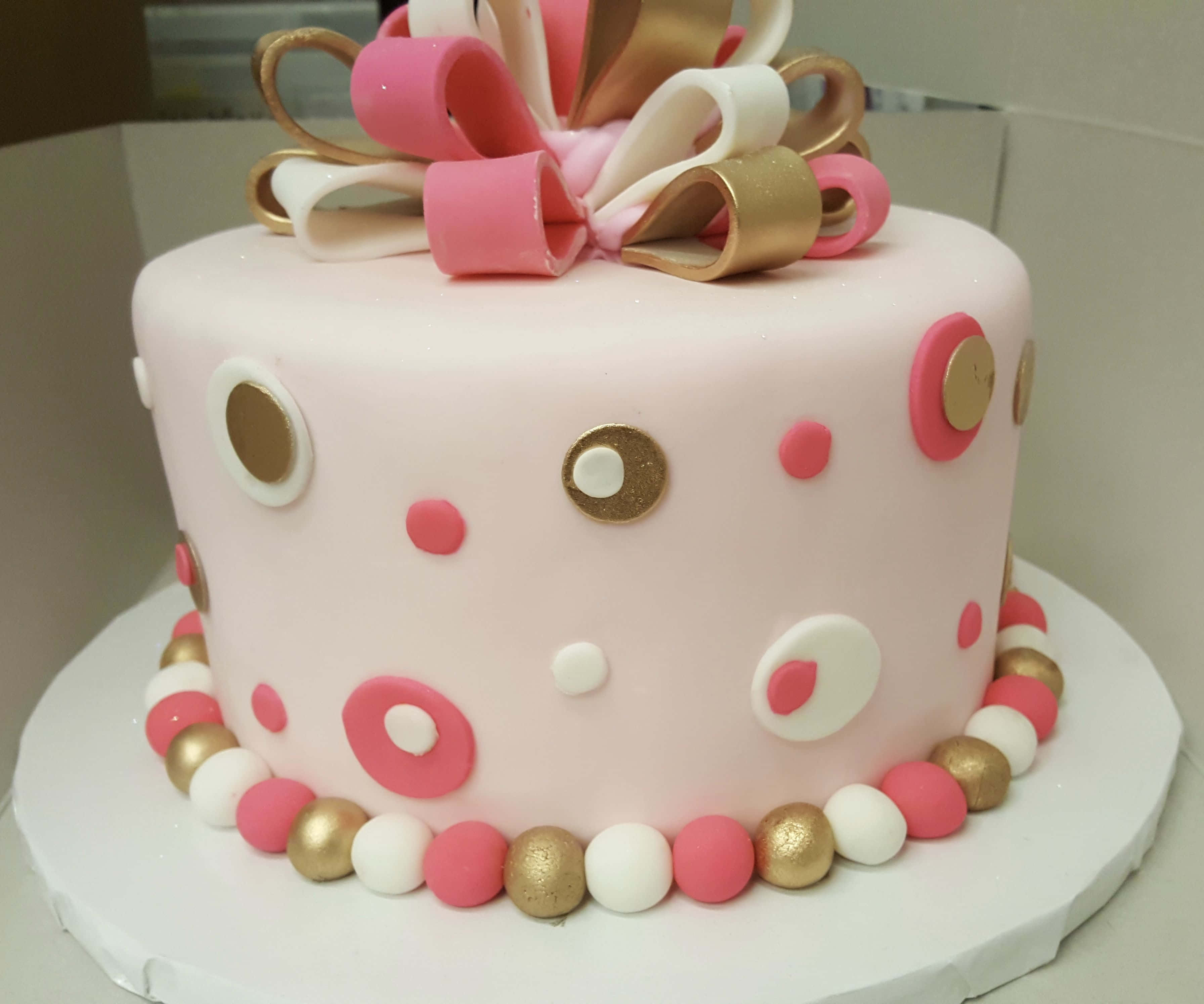 Cake Fondant 桌布 壁紙 — 一個粉紅色翻糖蛋糕，飾有粉紅、白色和金色的圓點，頂部有一個大蝴蝶結。