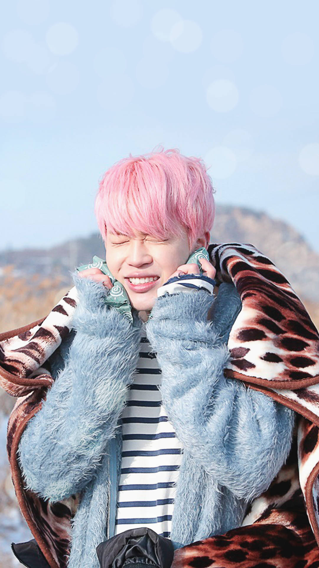 Jimin Bts Cute 桌布 壁紙 — 一個粉紅色頭髮的人在晴朗的日子裡在戶外開心笑著，包裹著一條豹紋毯。