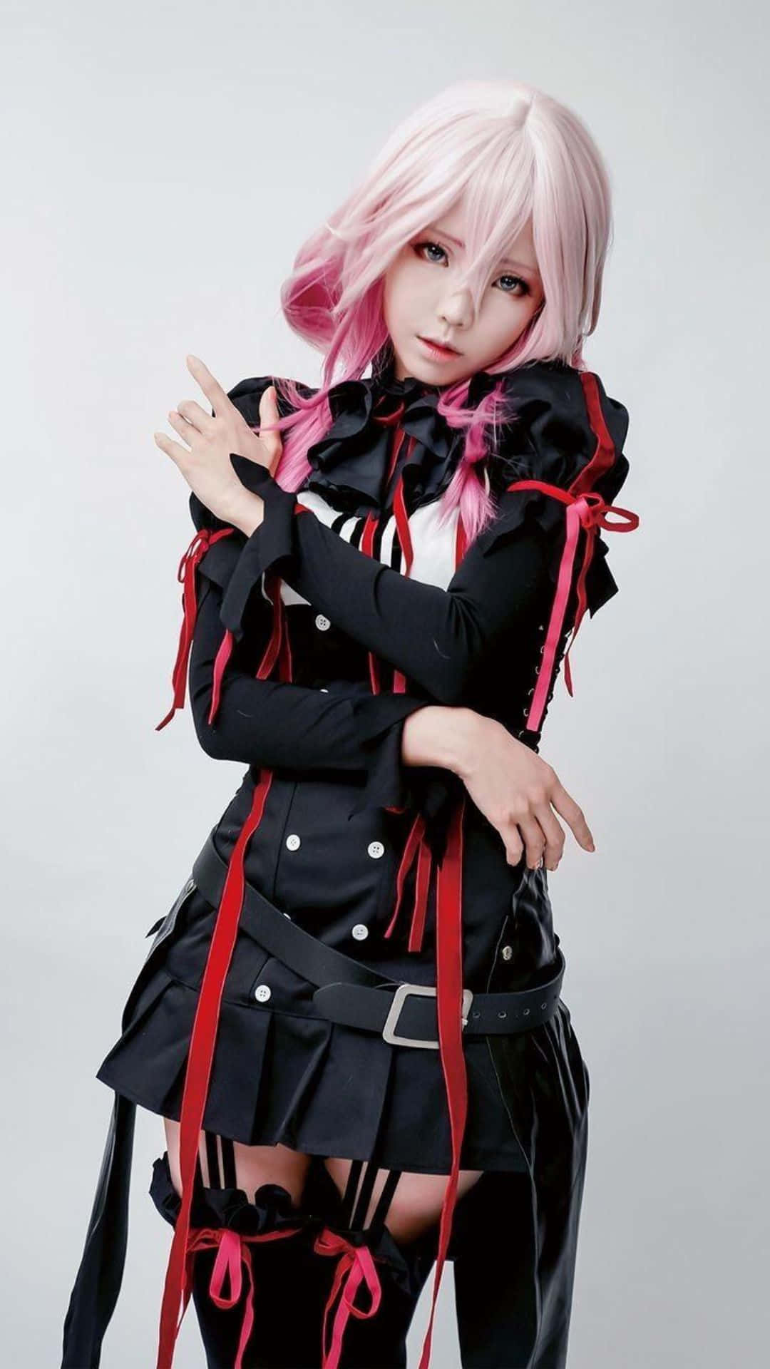 Cosplay Anime Kawaii 桌布 壁紙 — 一個粉紅色頭髮的人穿著黑色和紅色的哥德式服裝，在純灰色背景前擺姿勢。