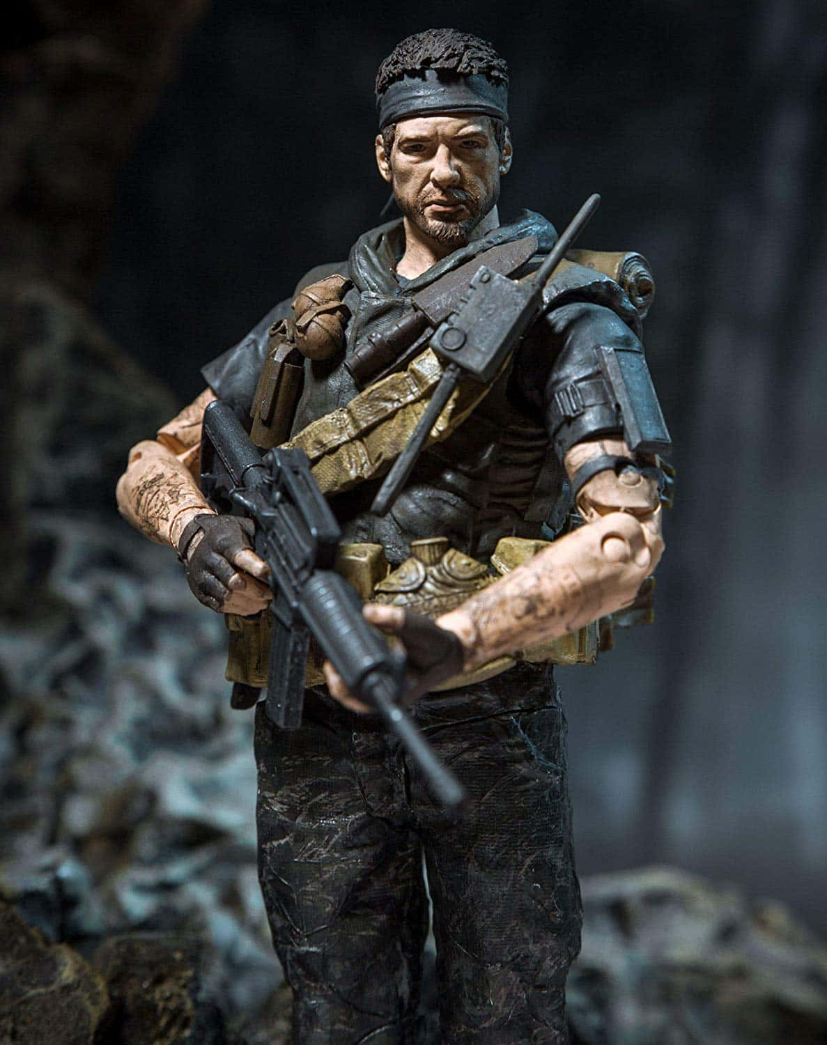 Frank Woods 桌布 壁紙 — 一個粗獷的動作人偶，描繪一位留鬍鬚的士兵穿著戰術裝備，在黑暗岩石背景下手持突擊步槍。