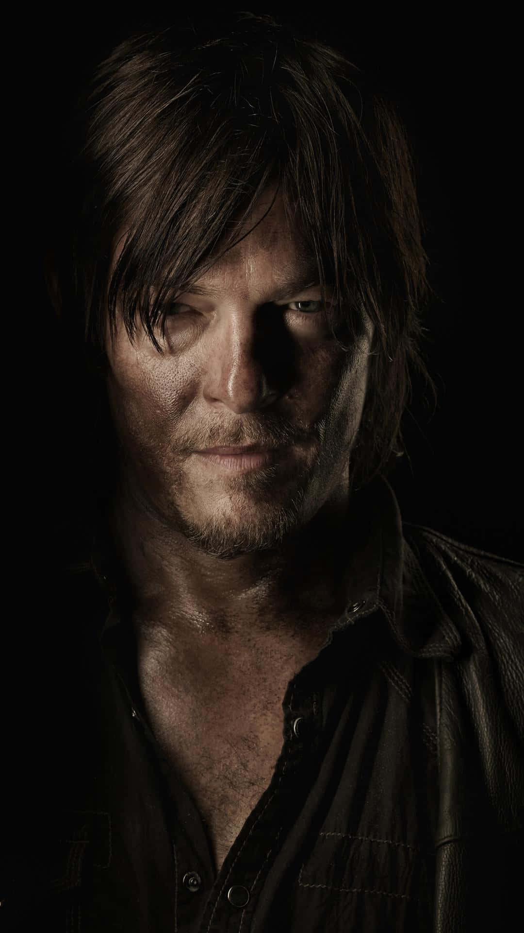 The Walking Dead iPhone 桌布 壁紙 — 一個粗獷的特寫肖像，一個黑髮、鬍渣的男人，穿著皮夾克，背景為黑色。