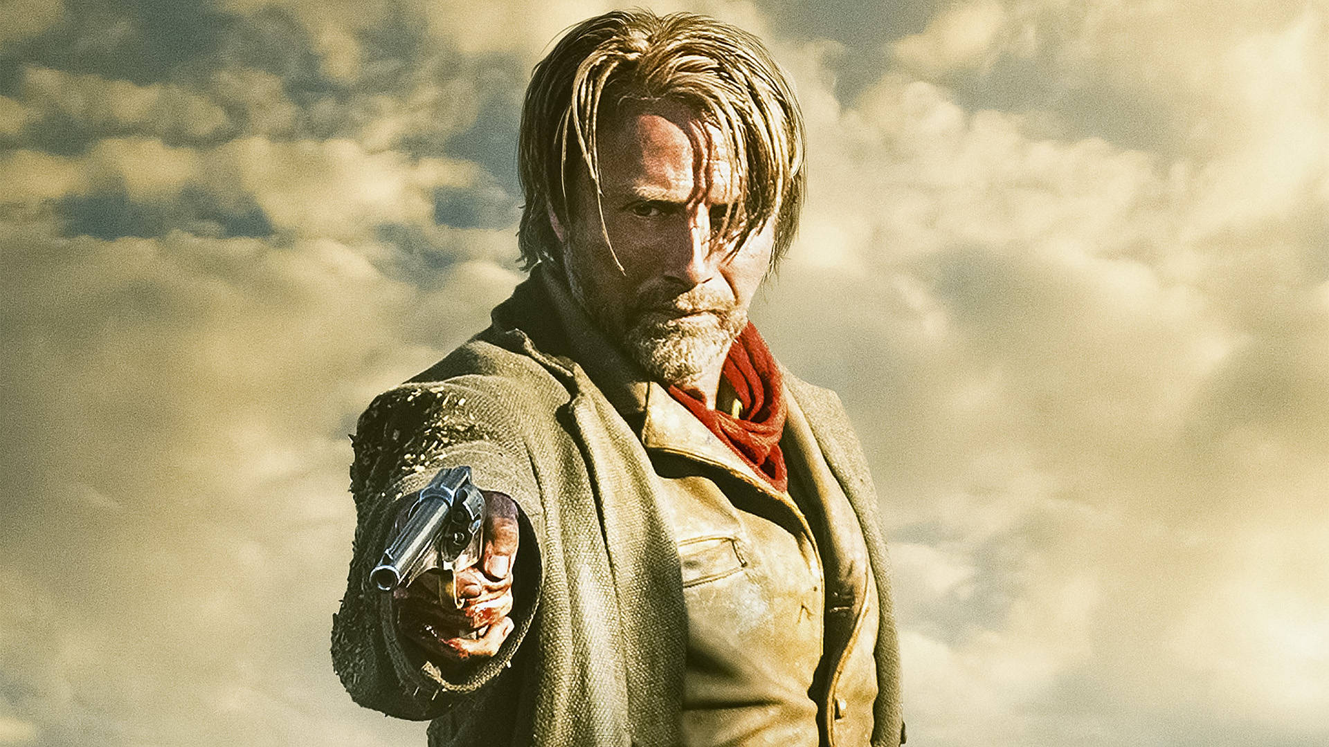 Mads Mikkelsen 桌布 壁紙 — 一個粗獷的男人，留著鬍鬚，戴著紅色圍巾，在多雲的天空背景下，用左輪手槍直接瞄準觀眾。