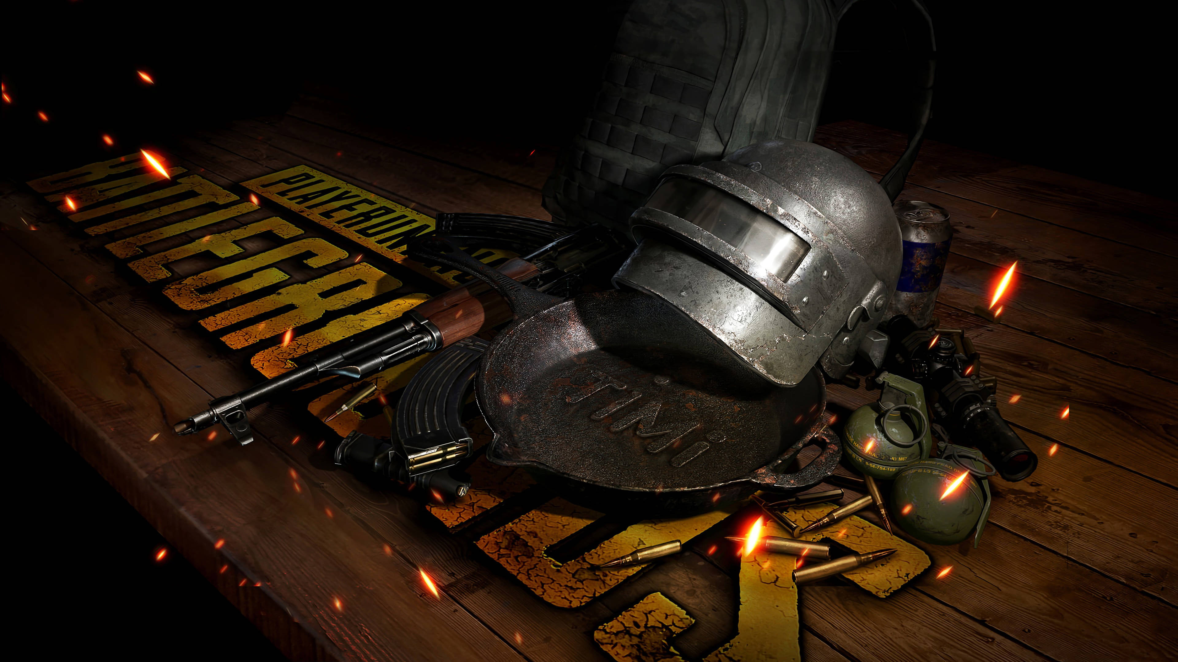 絕地求生 桌布 壁紙 — 一個粗糙的PUBG頭盔、步槍和裝備放在木桌上，火花在遊戲標誌周圍飛舞。