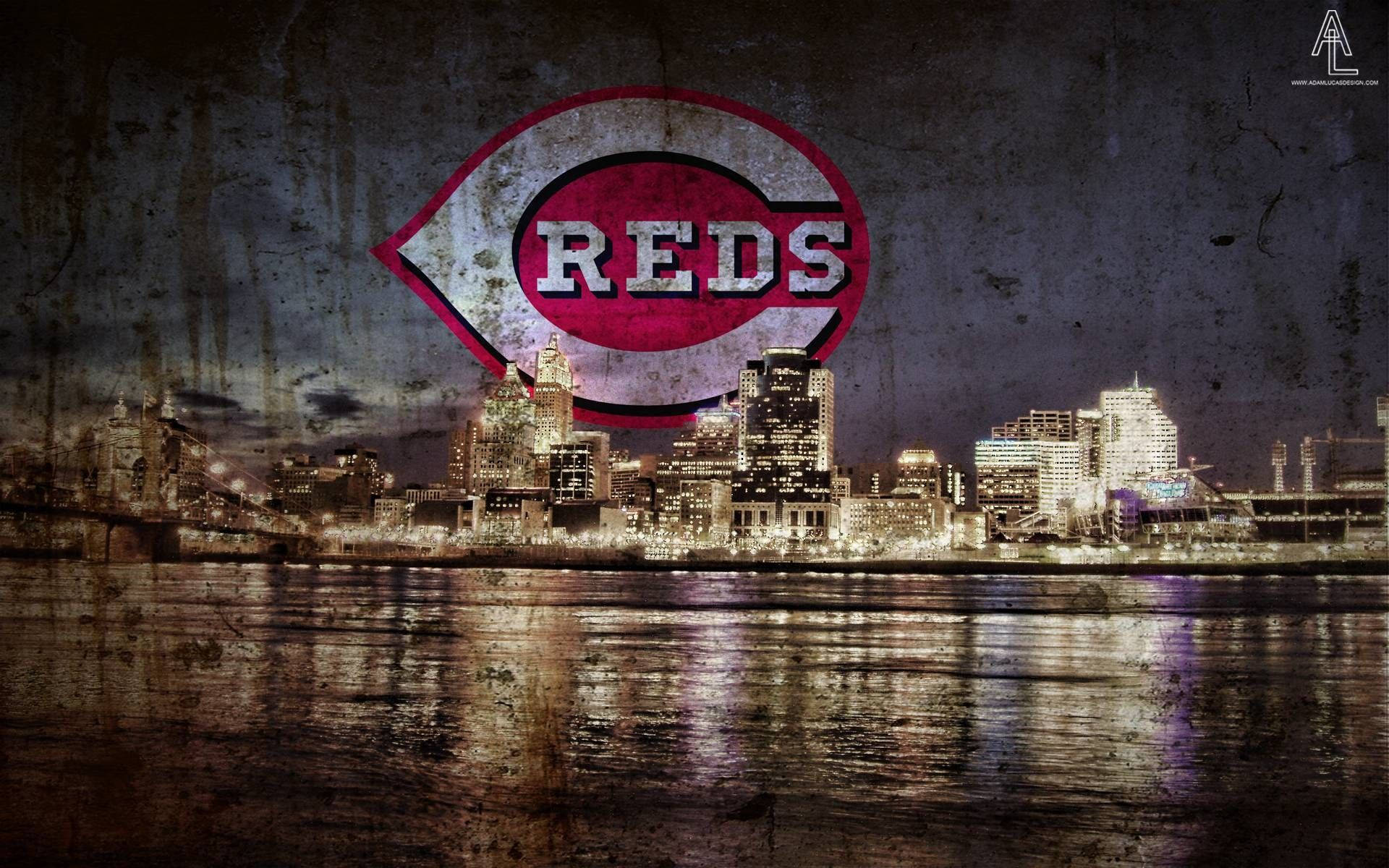 Reds 桌布 壁紙 — 一個粗糙的夜間城市景觀，辛辛那提紅人隊的大型標誌疊加在天際線和水面倒影上。