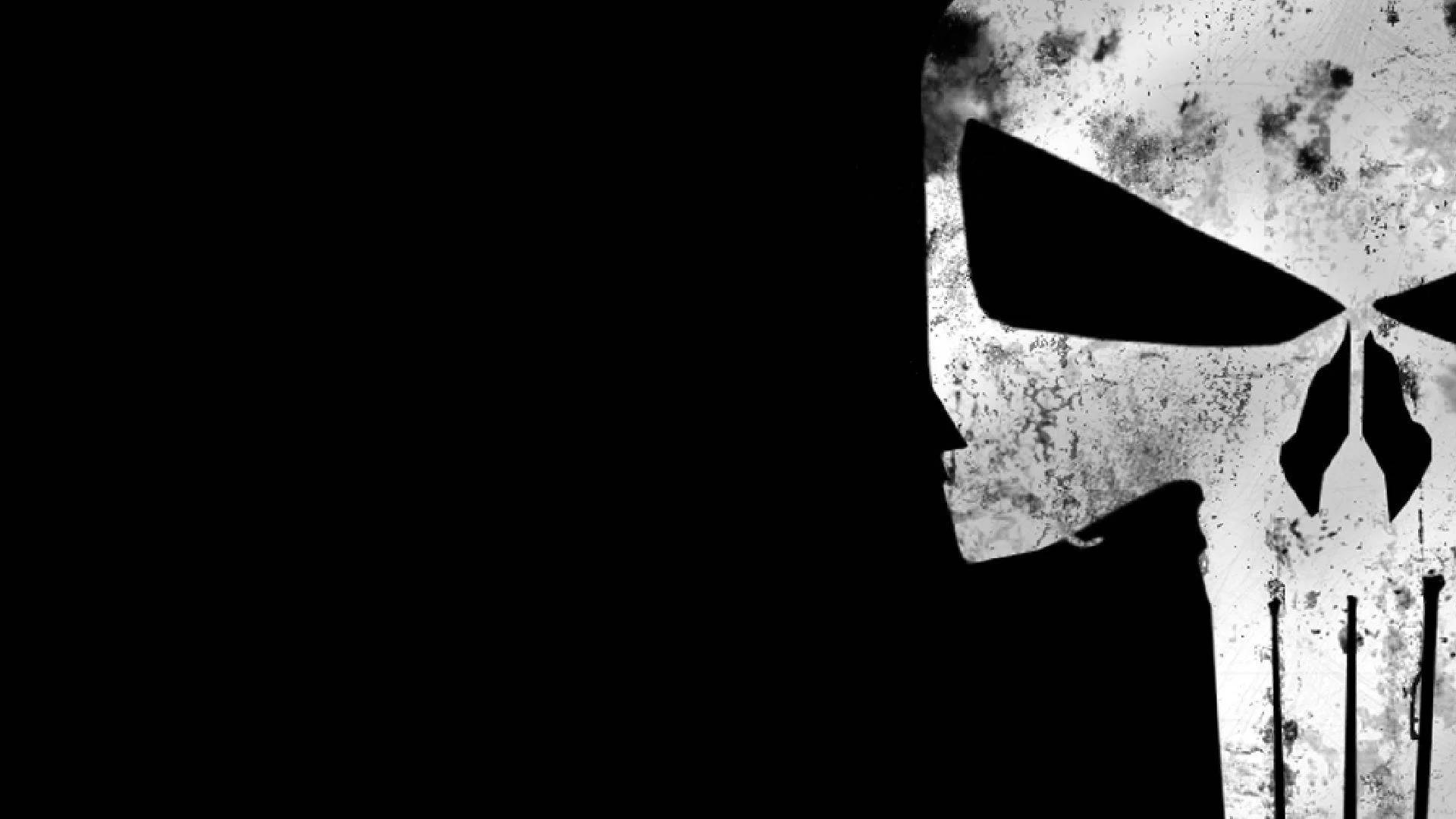 Punisher Logo 桌布 壁紙 — 一個粗糙的白色骷髏頭，帶有黑色眼窩和牙齒，在純黑色背景上顯得格外突出。