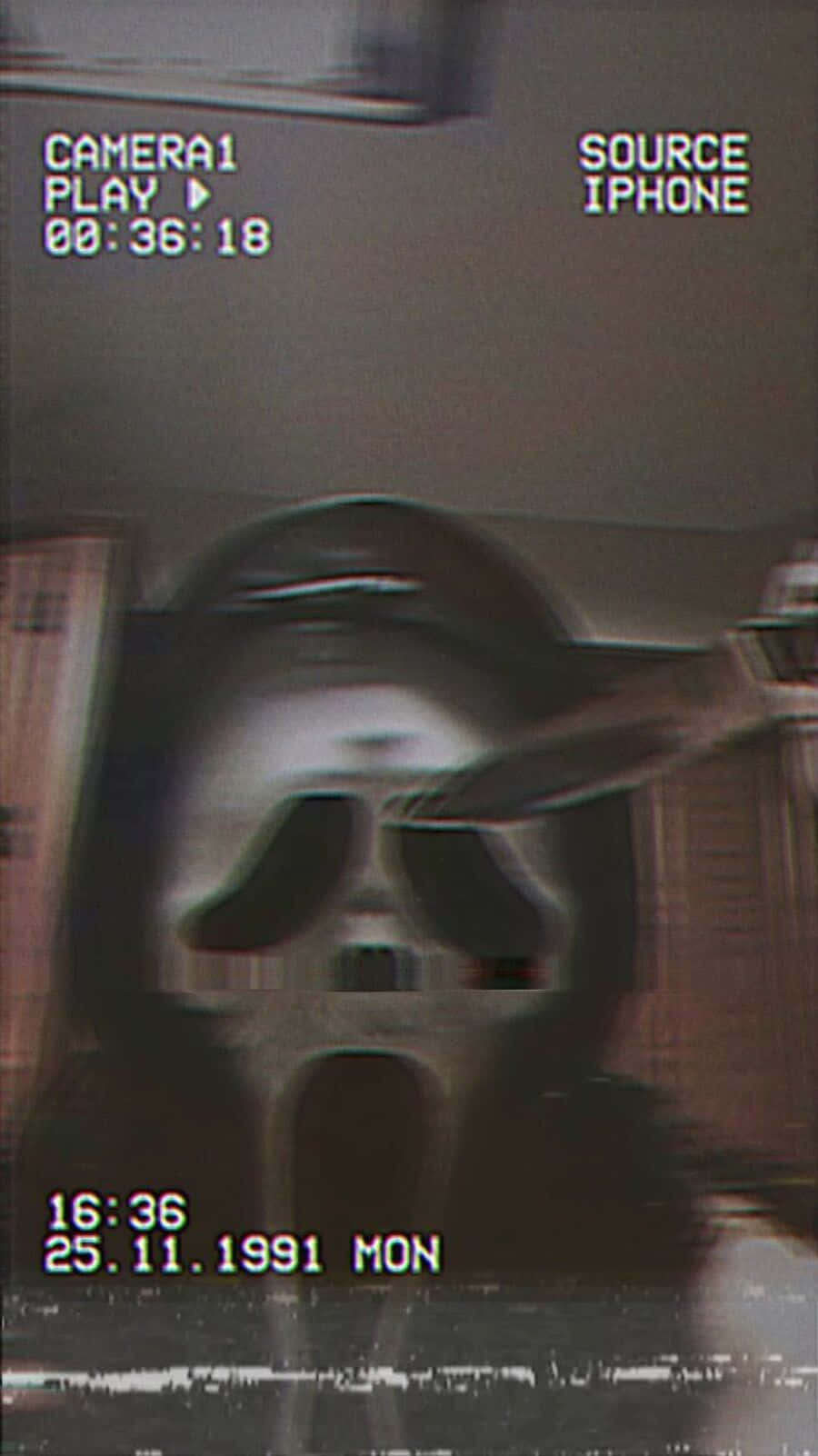Ghostface Aesthetic 桌布 壁紙 — 一個粗糙的監視器畫面顯示一個幽靈般的身影，戴著白色面具，面具上有尖叫的臉，在昏暗的房間裡。