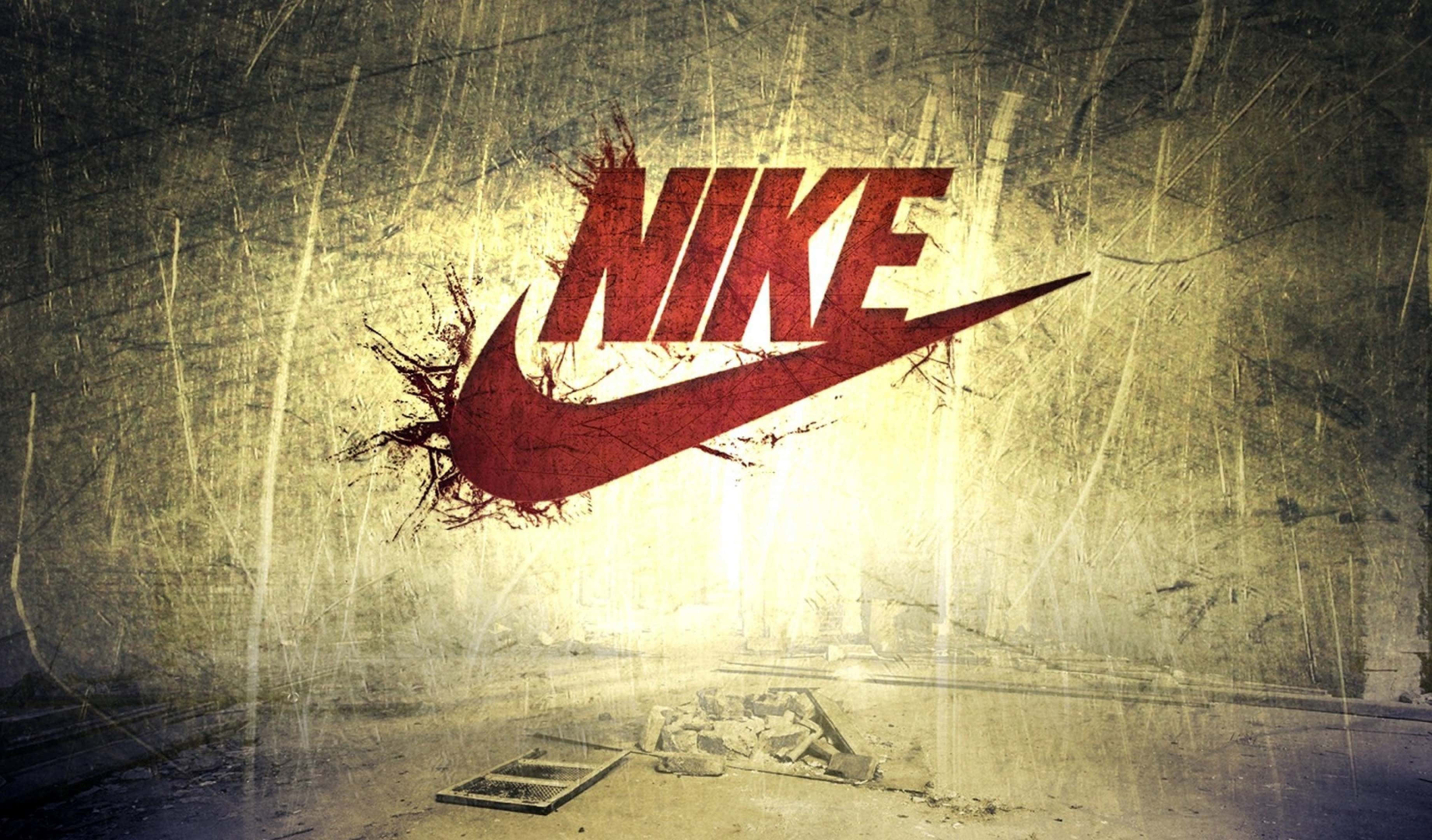 Nike 桌布 壁紙 — 一個粗糙的紅色Nike標誌穿過風化的混凝土牆，下方散落著碎片。