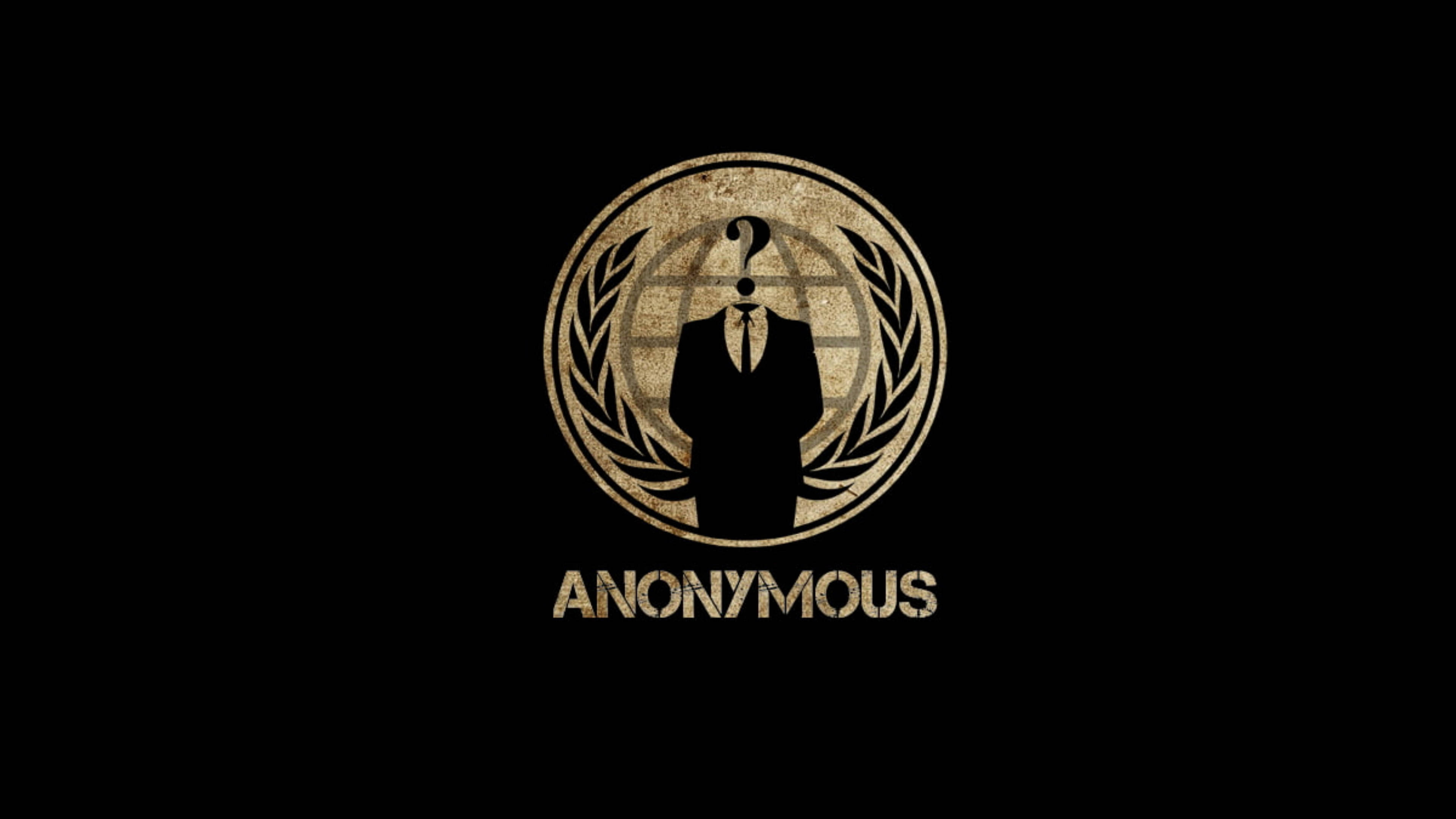 駭客 桌布 壁紙 — 一個粗糙的金色Anonymous標誌，帶有問號頭和月桂花環，背景為黑色。