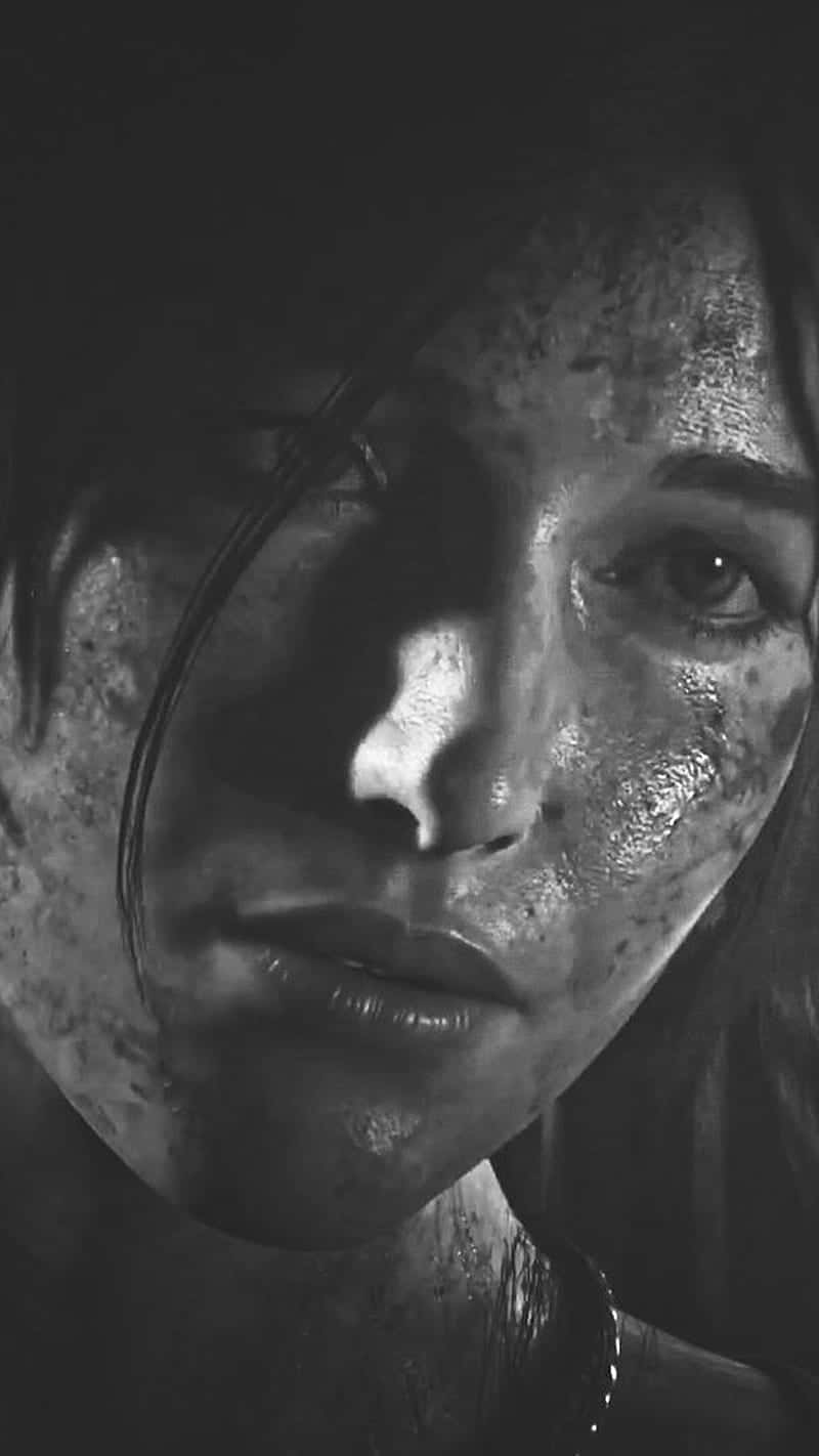 iPhone Xs Rise Of The Tomb Raider 桌布 壁紙 — 一個粗糙的黑白特寫，女人的臉上沾滿泥巴和汗水，在戲劇性的燈光下。