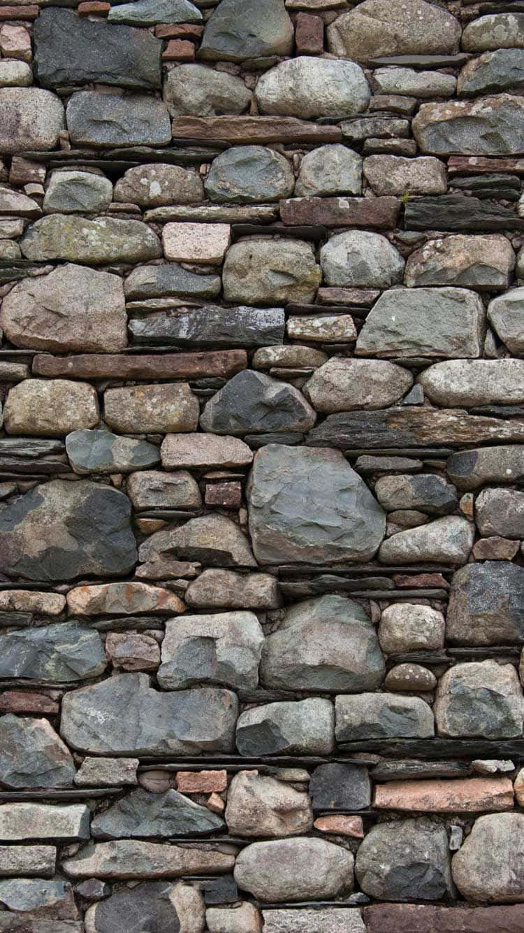 wall 桌布 壁紙 — 一個粗糙石牆的特寫，由各種灰色、棕色和棕褐色岩石堆疊成不均勻的水平行。