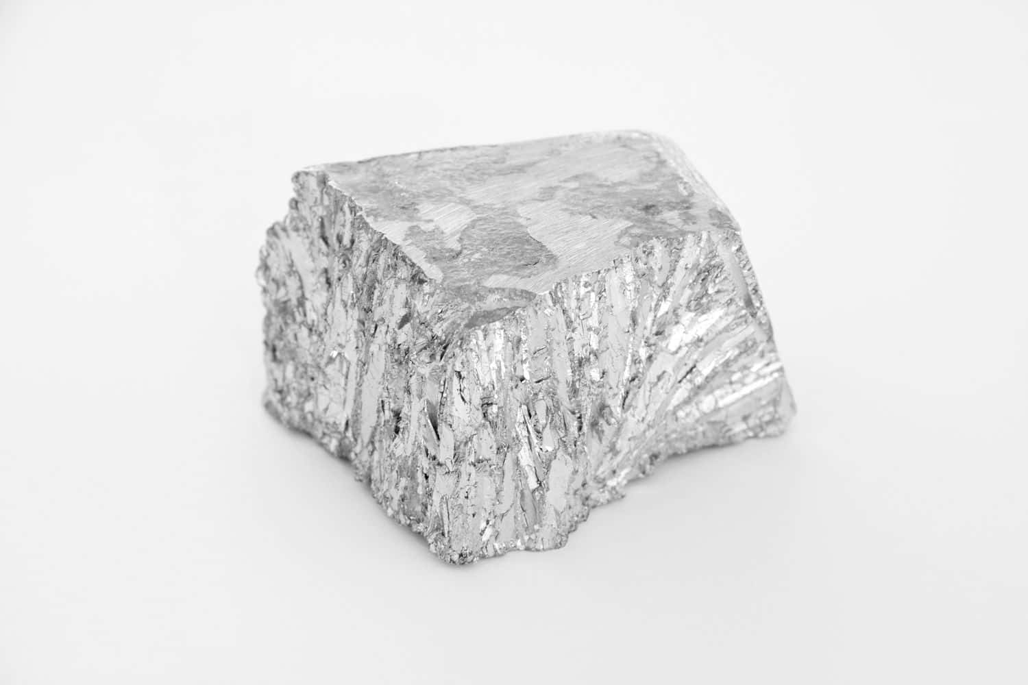 金屬質感 桌布 壁紙 — 一個粗糙紋理的銀色金屬塊，邊緣參差不齊，孤立地放在純白色背景上。