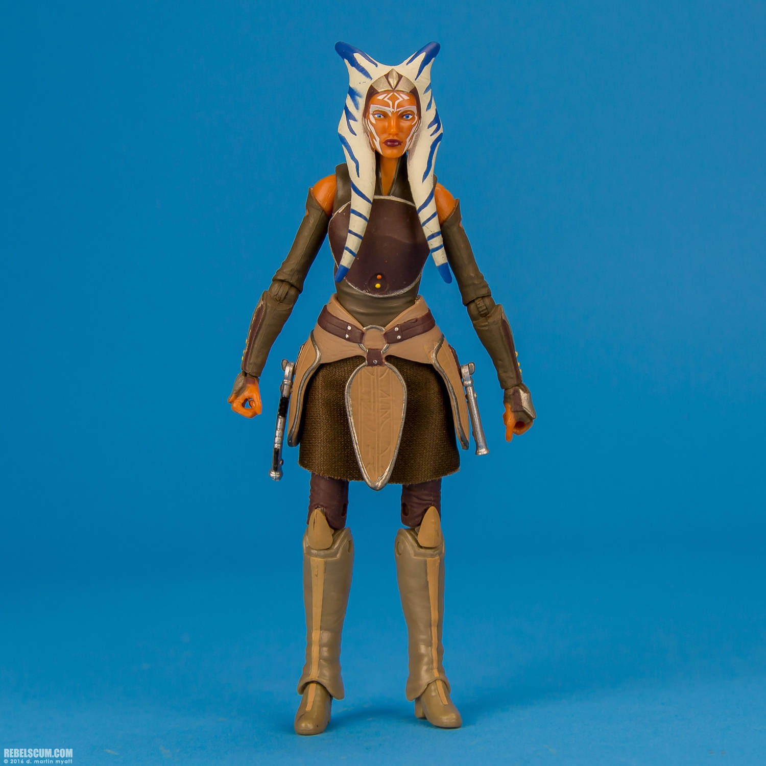 Animated 桌布 壁紙 — 一個精細的Ahsoka Tano可動人偶在純藍色背景前擺出姿勢，展示其標誌性的白色和藍色頭飾以及棕色盔甲。