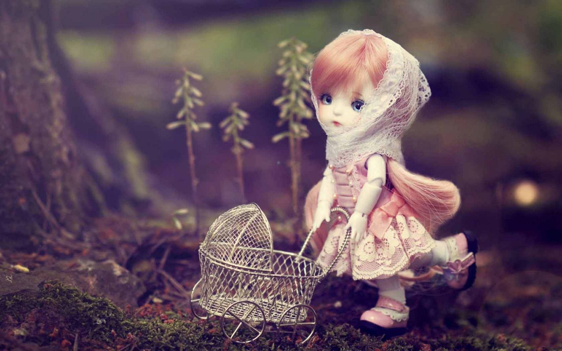 Doll 桌布 壁紙 — 一個精緻的洋娃娃，粉紅色頭髮和蕾絲面紗，推著一個小小的鐵絲嬰兒車穿過長滿苔蘚的森林地面。