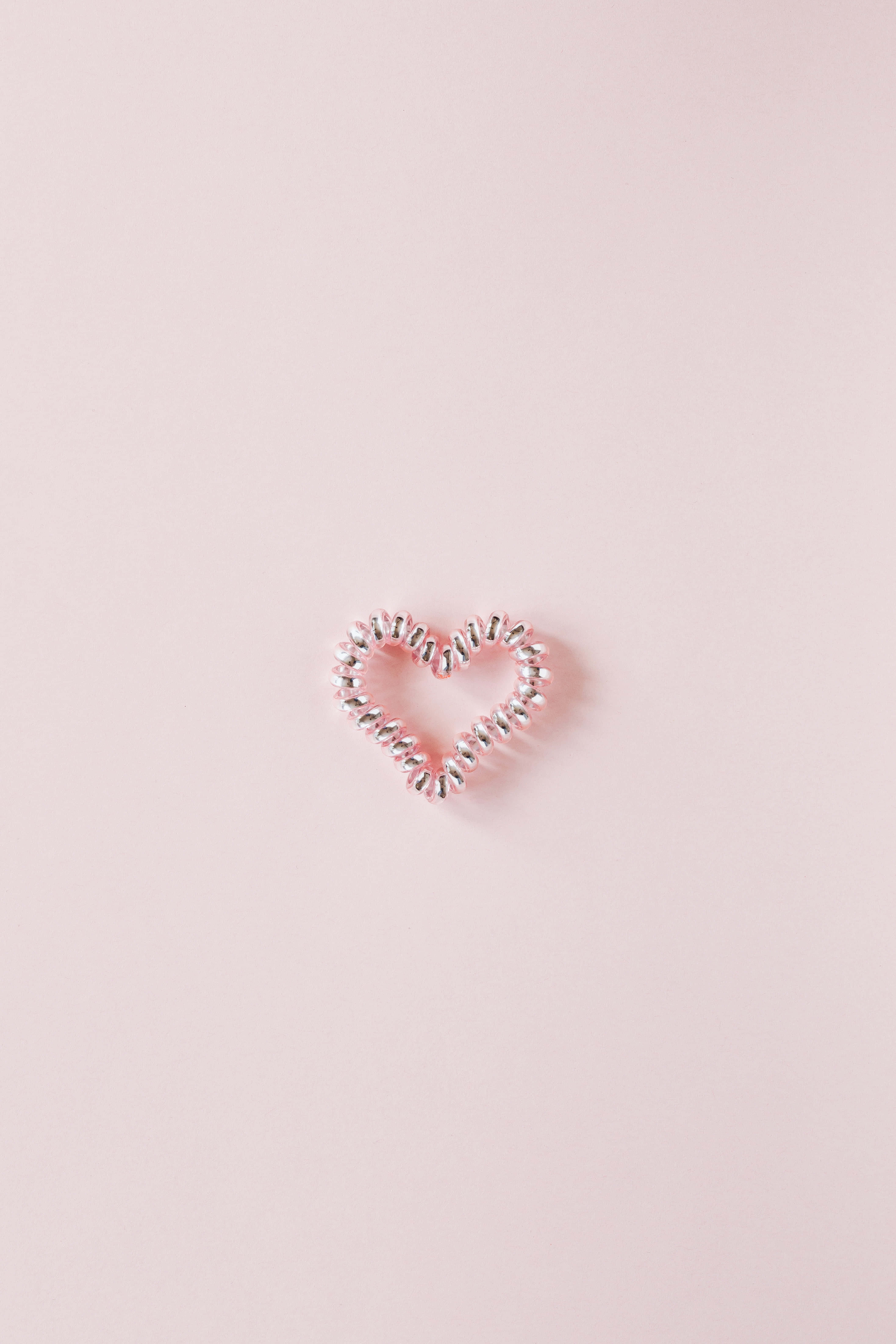 Simple Pink 桌布 壁紙 — 一個精緻的銀色心形髮圈放在柔軟的粉紅色背景中央。