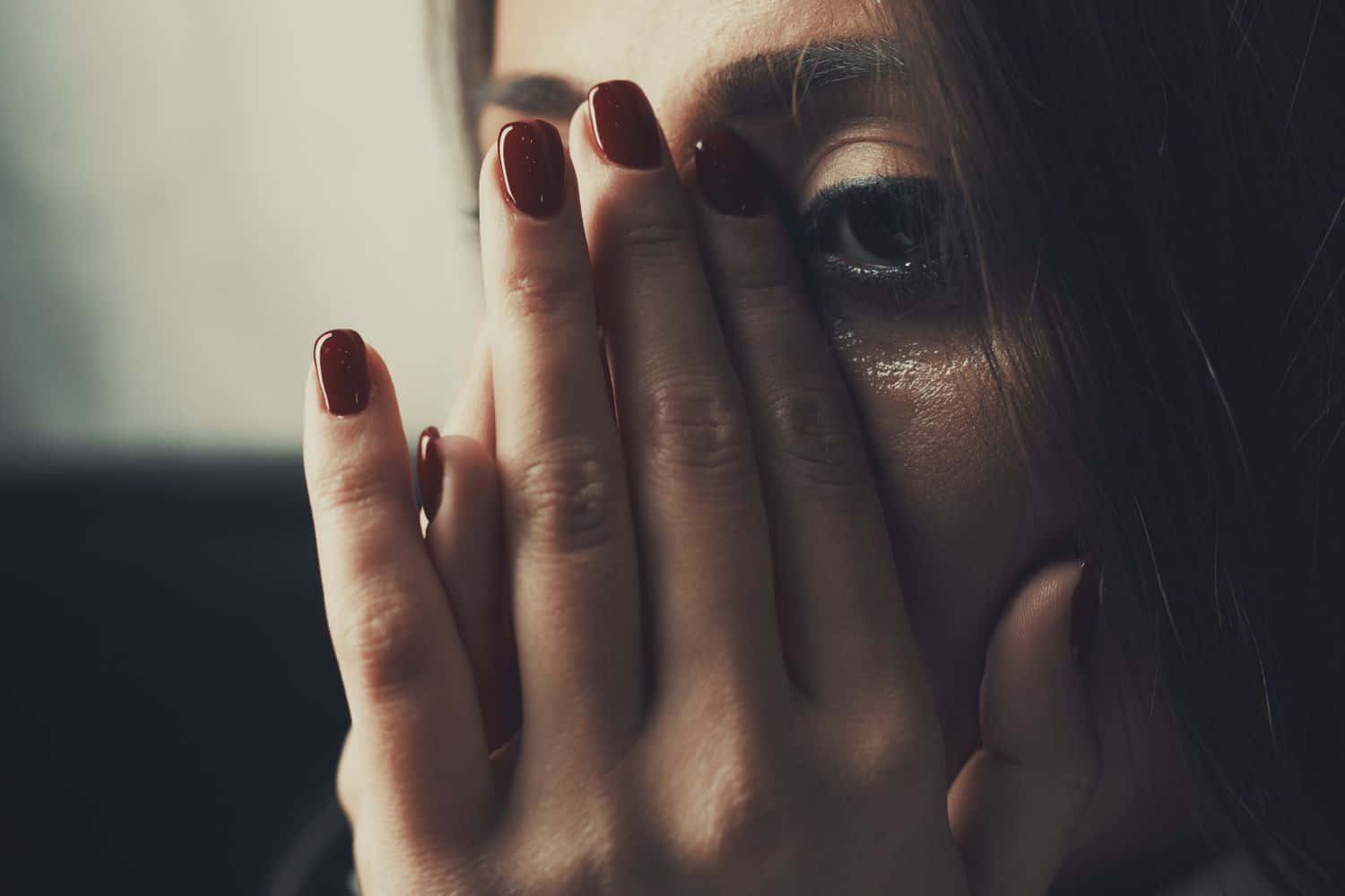 Man Crying 桌布 壁紙 — 一個紅指甲女人用一隻手遮住臉，在昏暗的特寫中露出一隻含淚的眼睛。