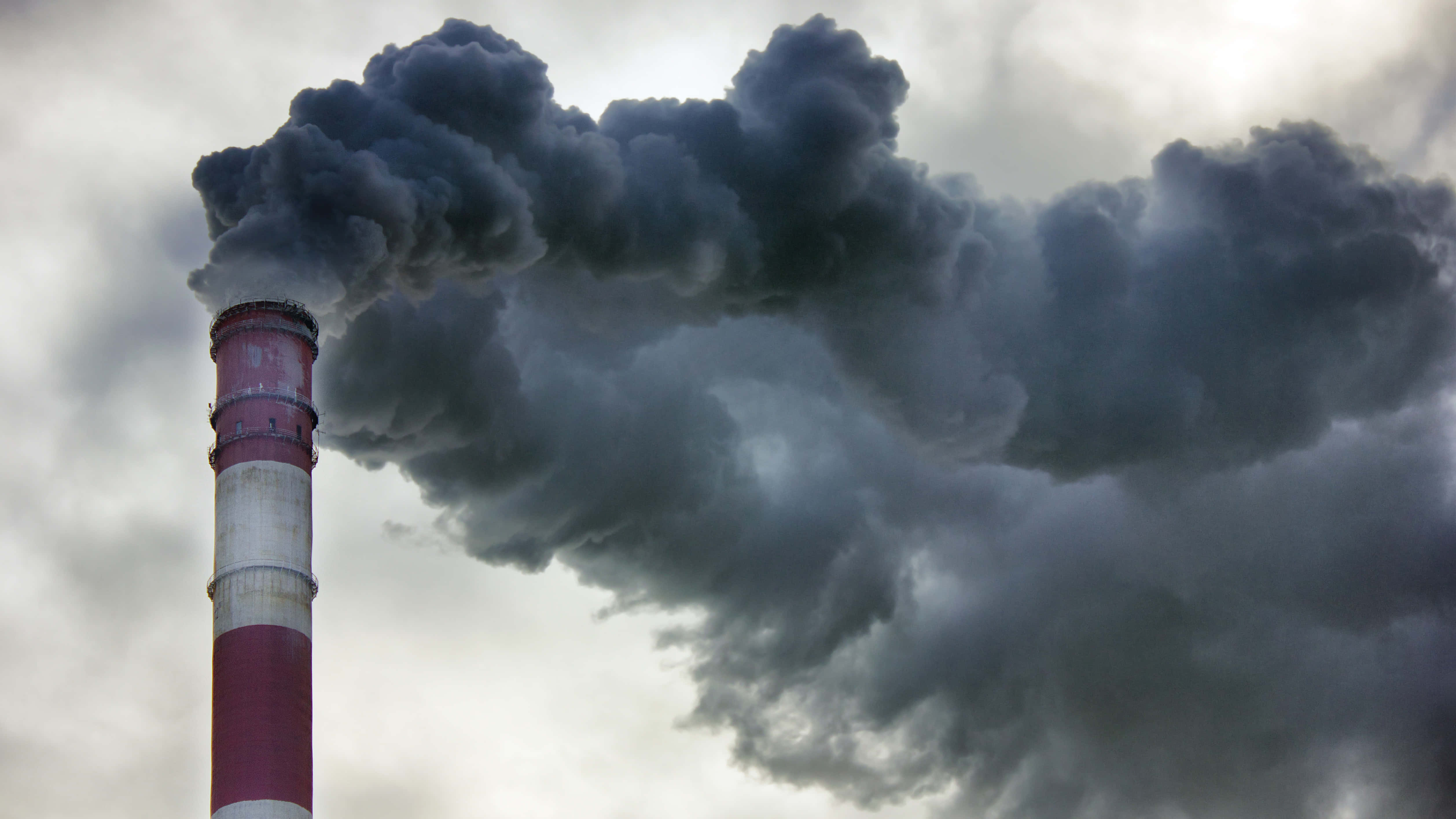 Pollution 桌布 壁紙 — 一個紅白相間的工業煙囪向多雲的灰色天空噴出濃厚的黑煙。