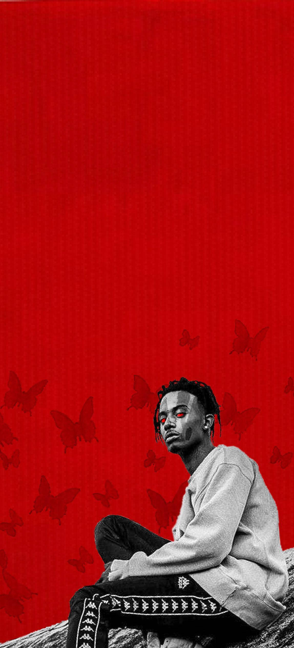 Carti 桌布 壁紙 — 一個紅眼睛的年輕男子平靜地坐在充滿漂浮蝴蝶的鮮紅色背景前。