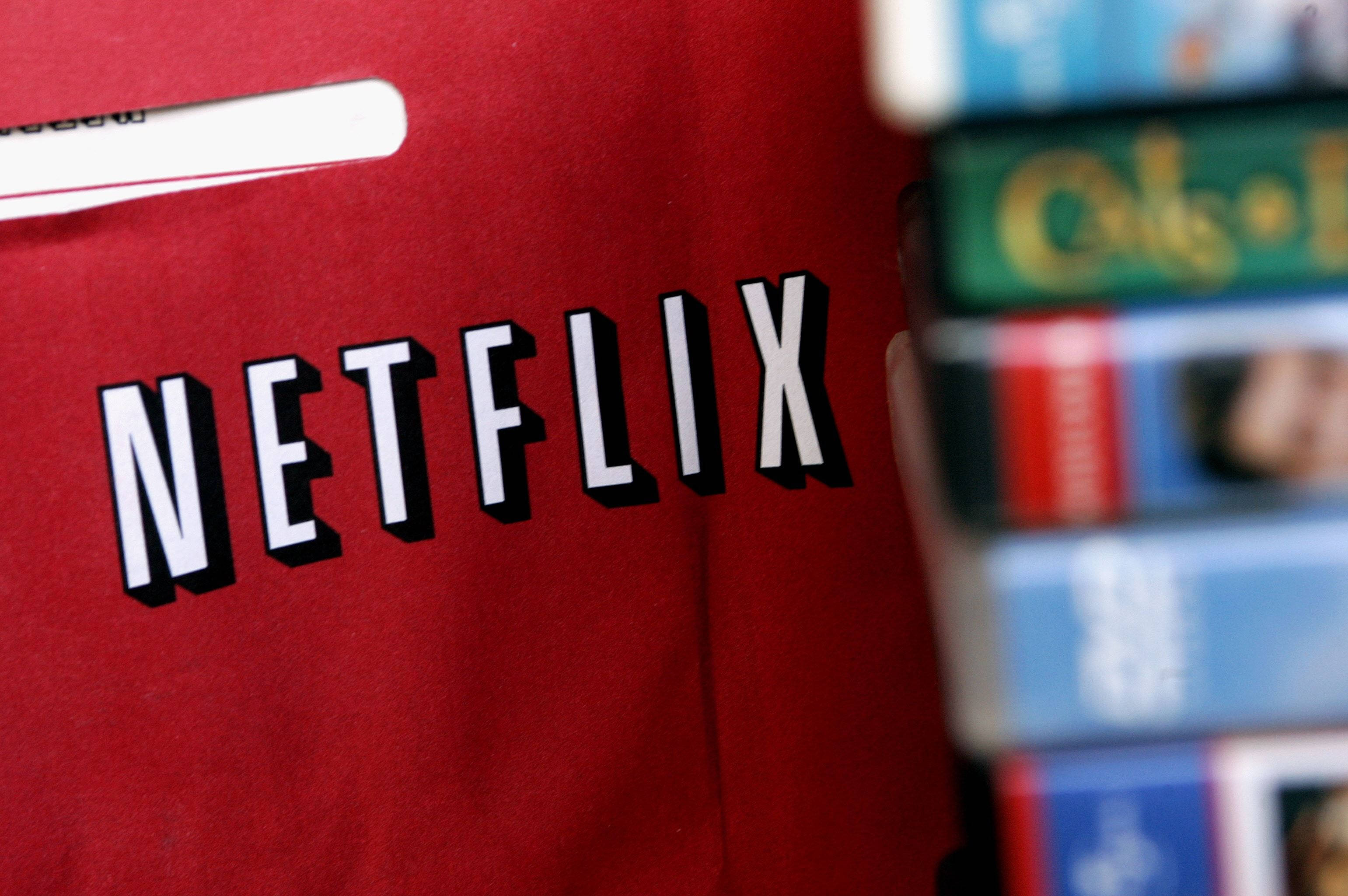 Netflix 桌布 壁紙 — 一個紅色Netflix袋的特寫，背景有一疊模糊的VHS錄影帶。