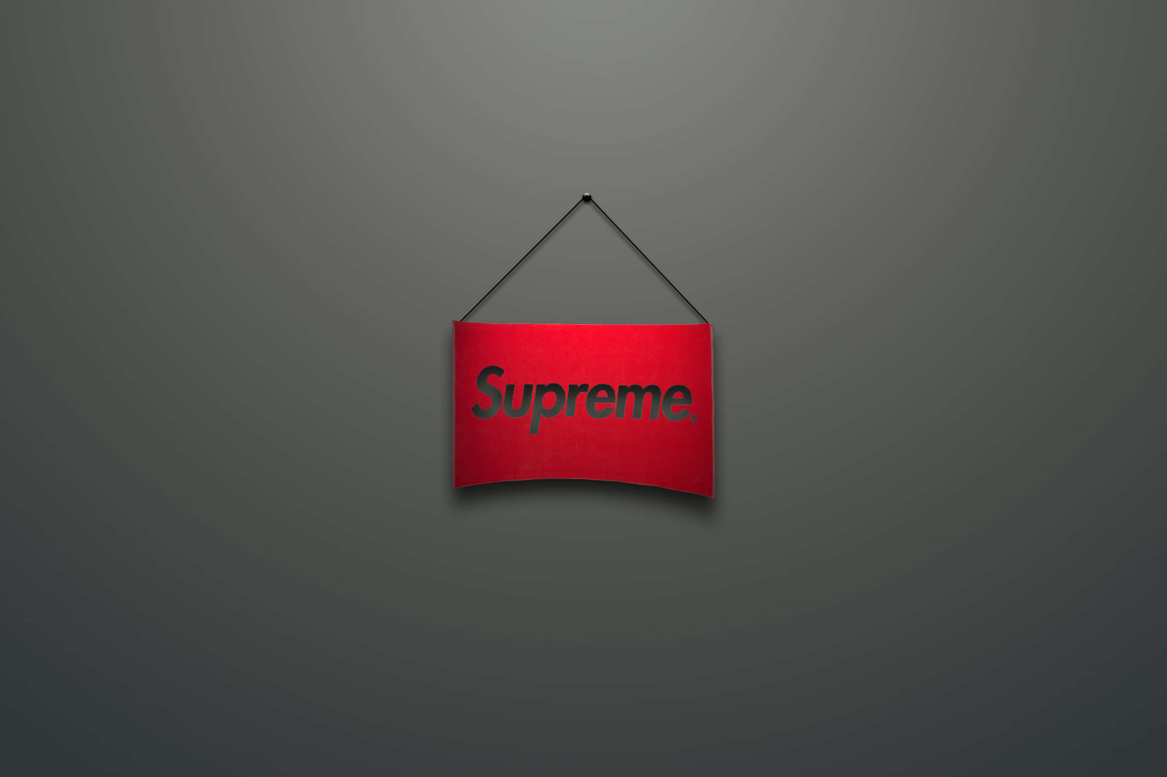 Supreme Logo 桌布 壁紙 — 一個紅色Supreme品牌標誌掛在漸變灰色牆壁中央，光線柔和。