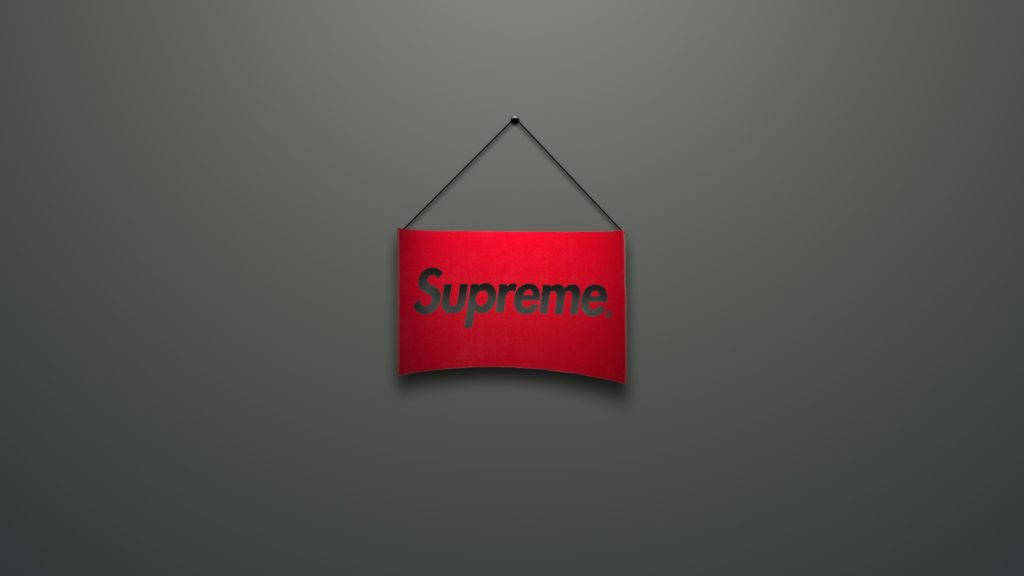 紅色至尊 桌布 壁紙 — 一個紅色Supreme標誌招牌掛在純深灰色牆壁中央，光線柔和。